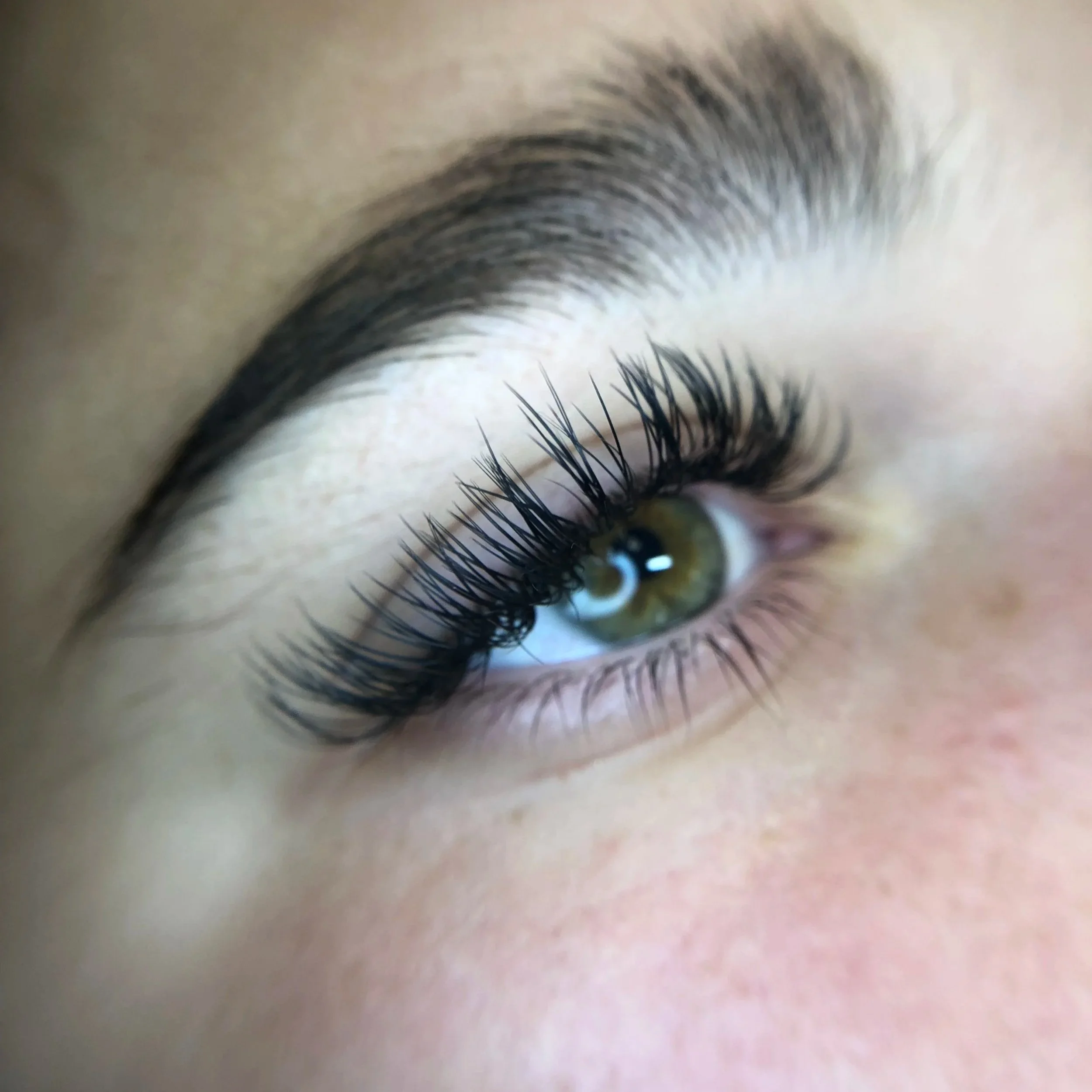Close-up of a person's eye with long, curled eyelashes and well-groomed eyebrow.