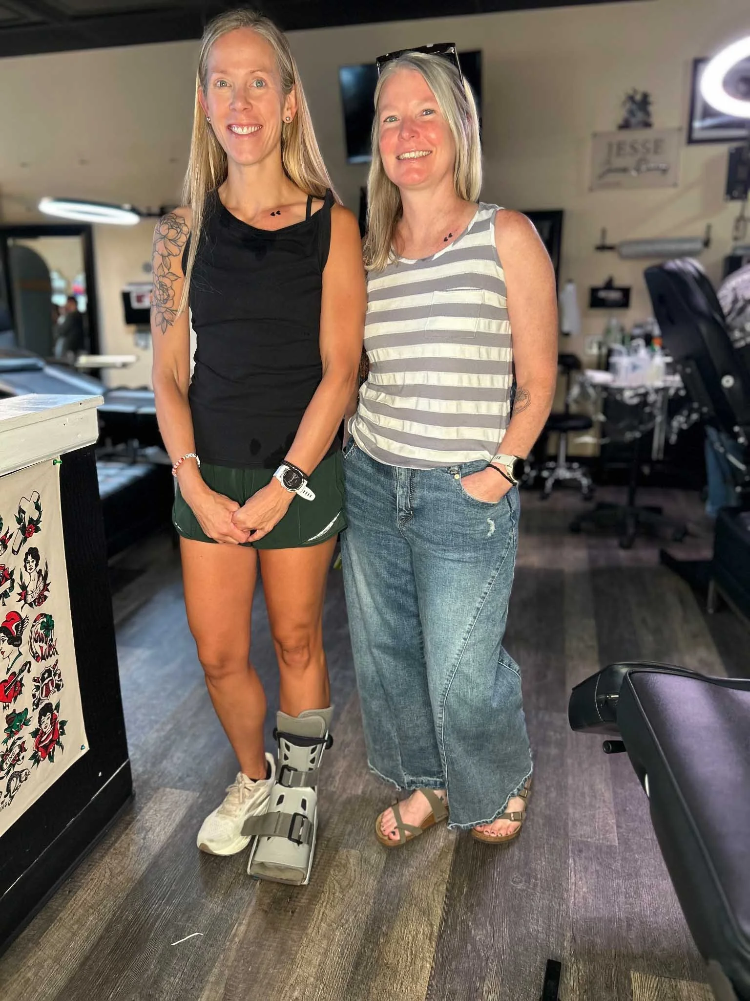 Two people standing in a studio displaying their tattoos