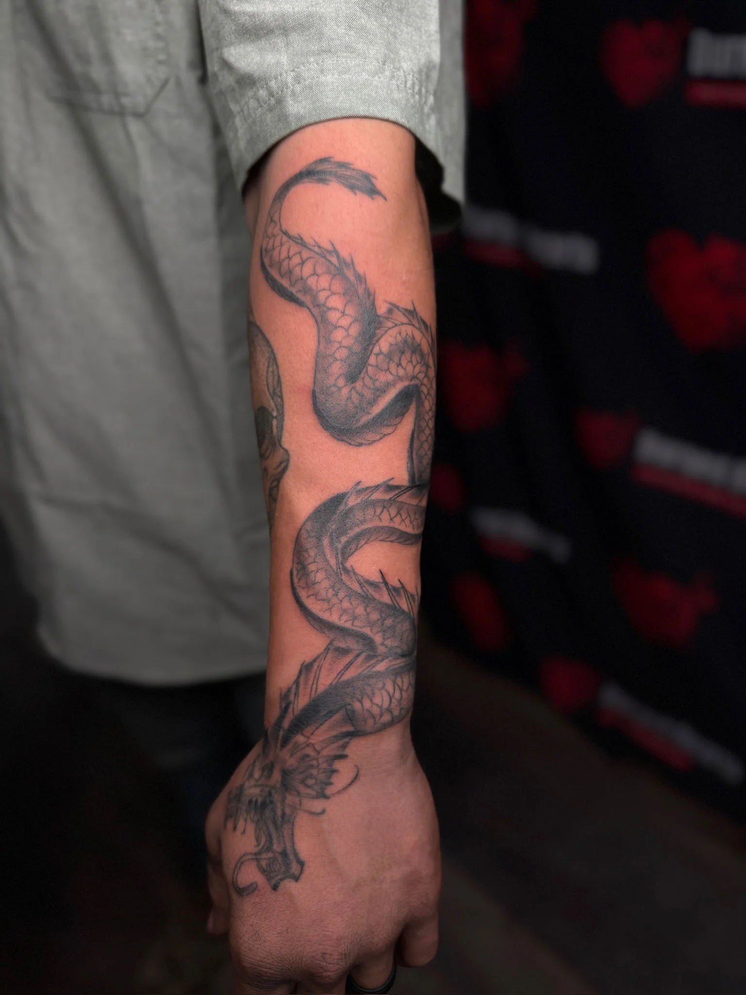 Black and gray dragon tattoo on person's forearm with detailed scales and wings.