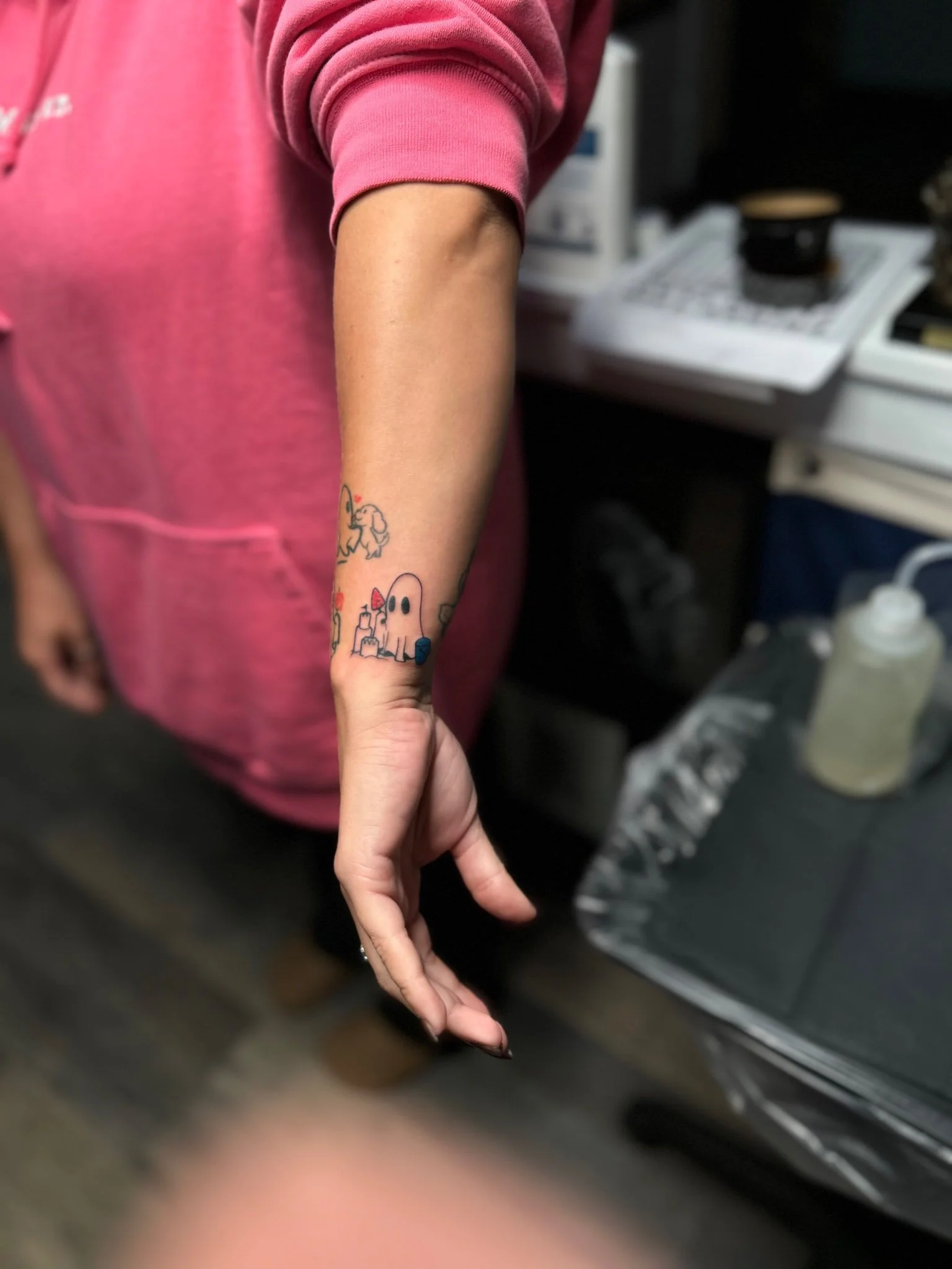 Person in a pink shirt displaying a fresh lower arm tattoo