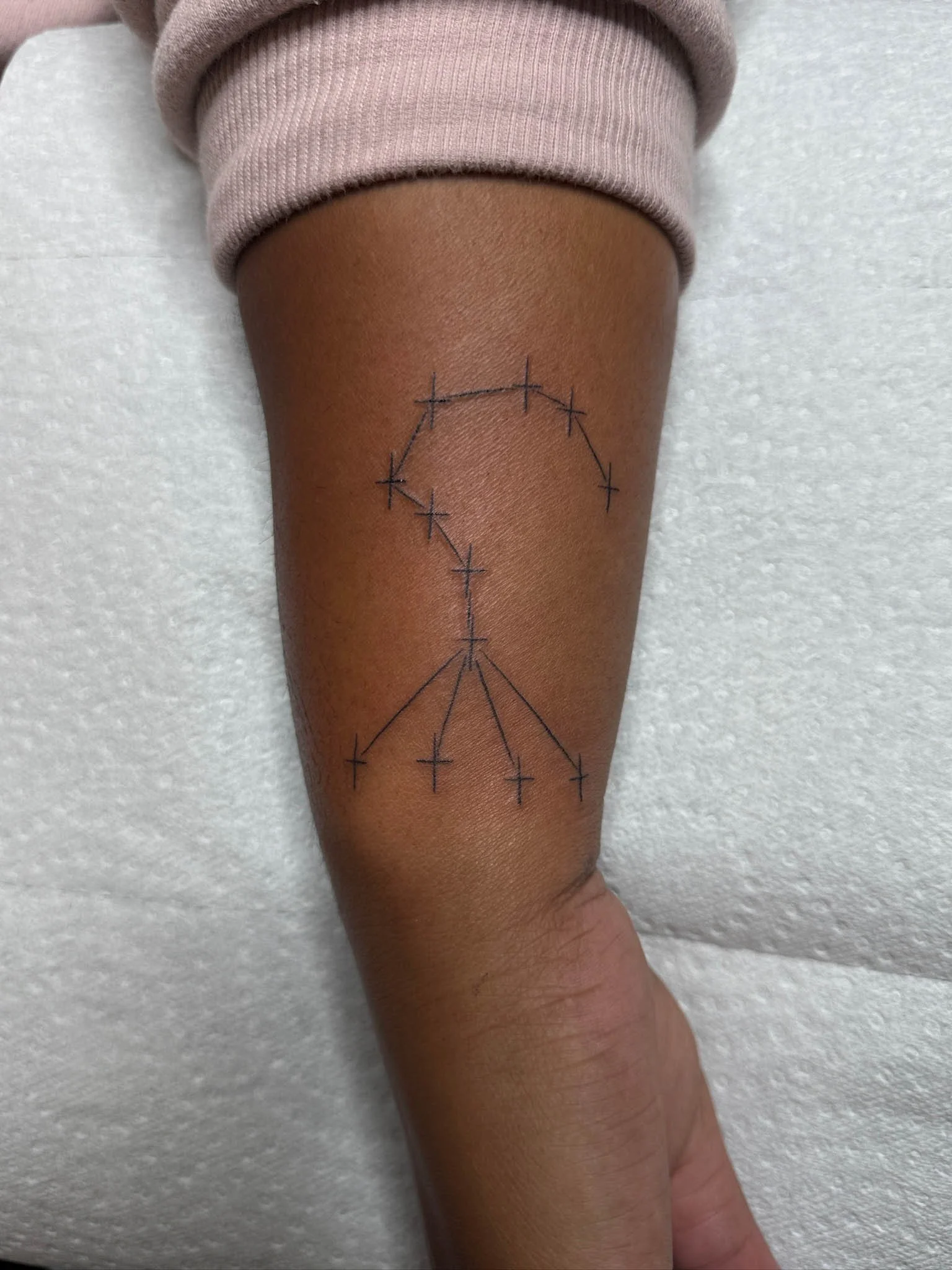 Tattoo of a peace sign with a rainbow arc above it, drawn on a person's thigh.