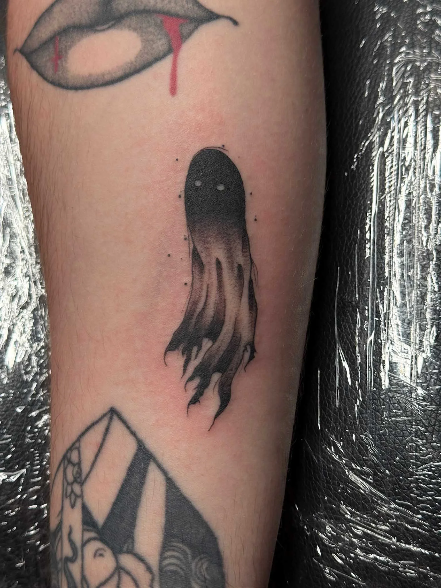Tattoo of a black and gray jellyfish on person's arm.