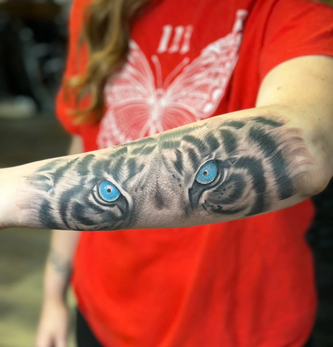 Close-up photograph of a tiger eye realism tattoo on forearm