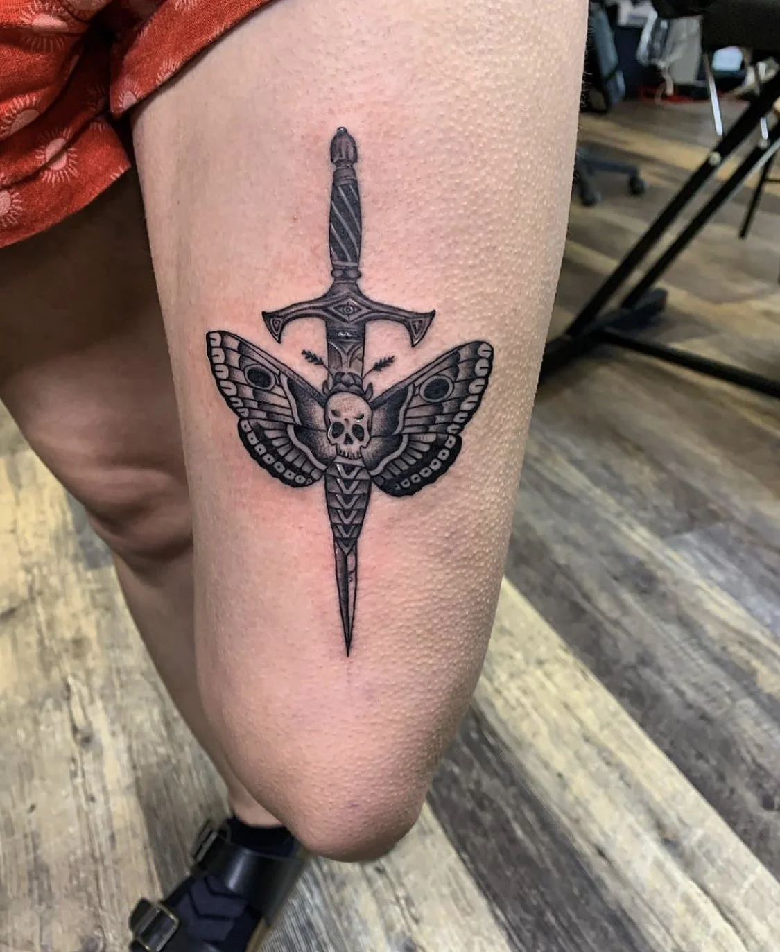 Close-up photograph of a sword and butterfly figure on thigh