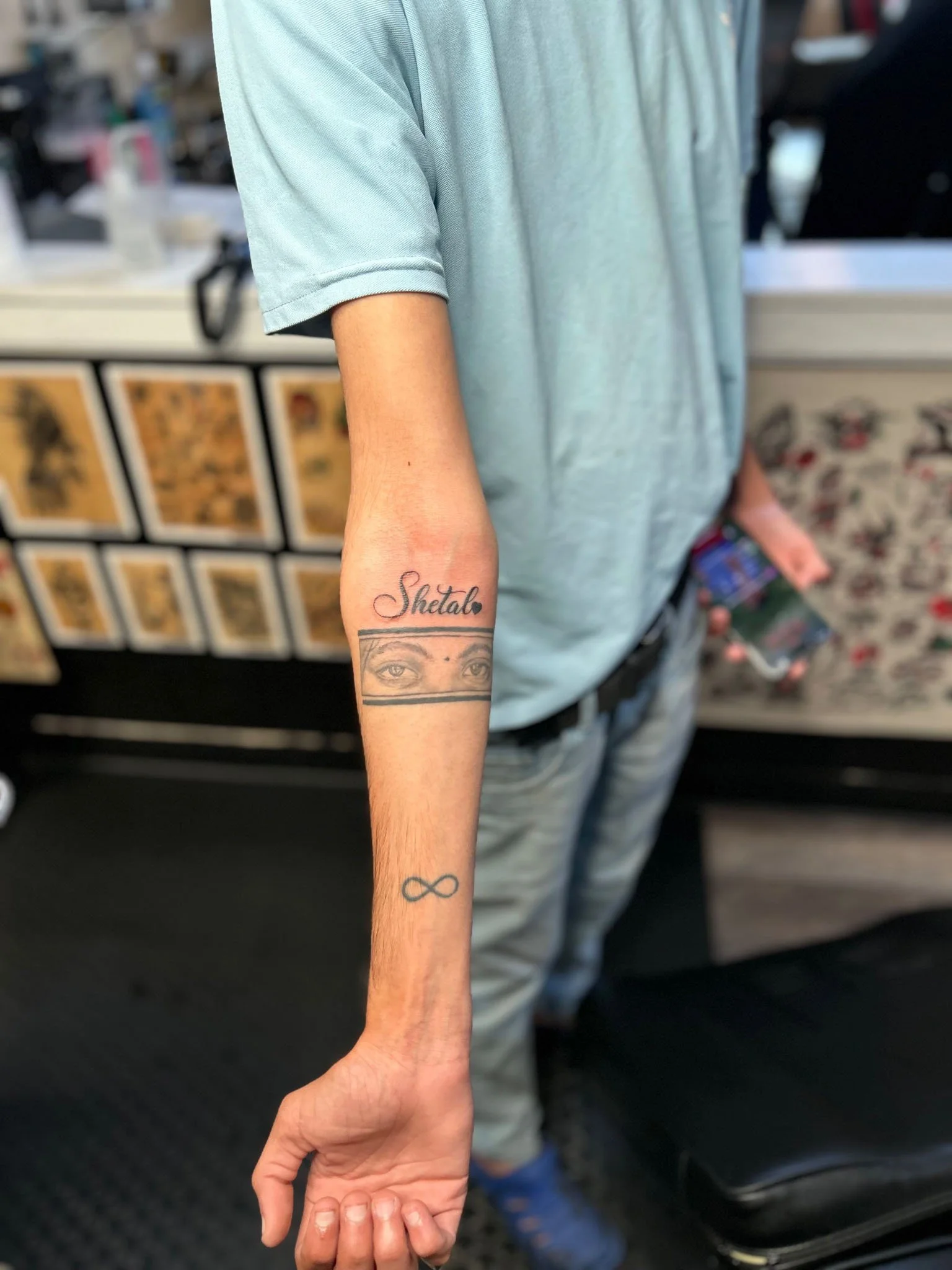 Script and eyes forearm tattoo displayed vertically