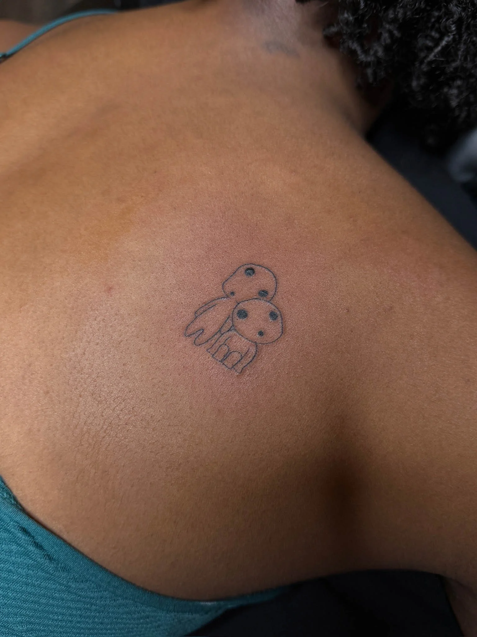 A small tattoo of two cartoon-style pandas on a person's upper chest or shoulder area.