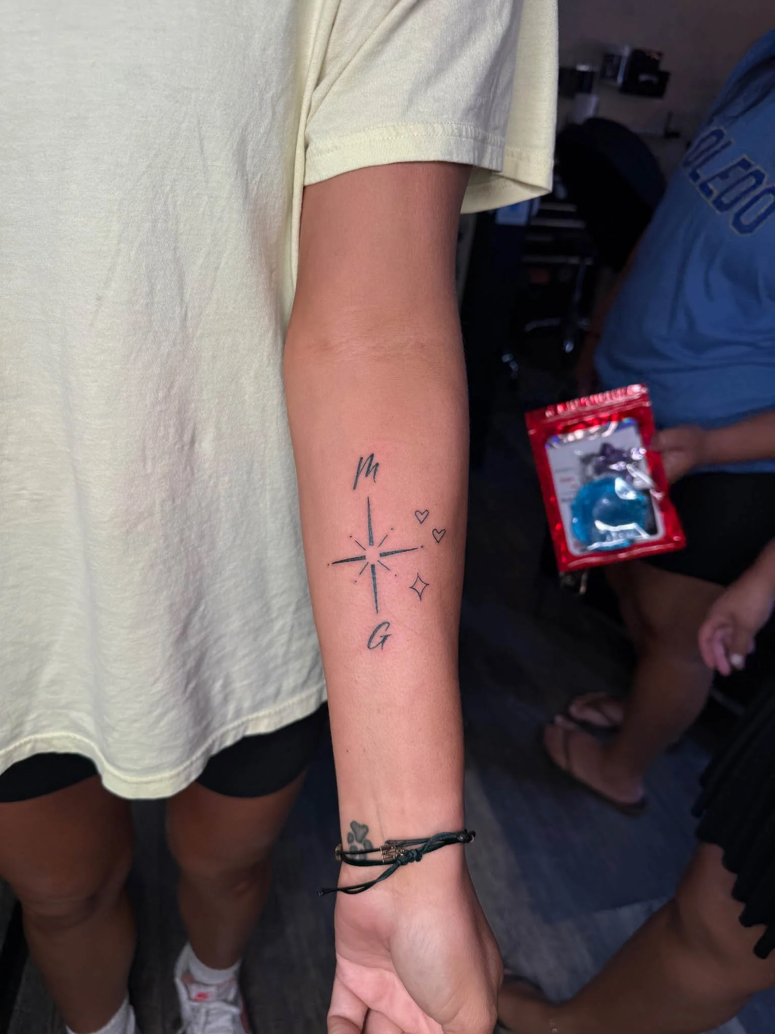 Minimalist fine-line starburst compass tattoo on an inner forearm