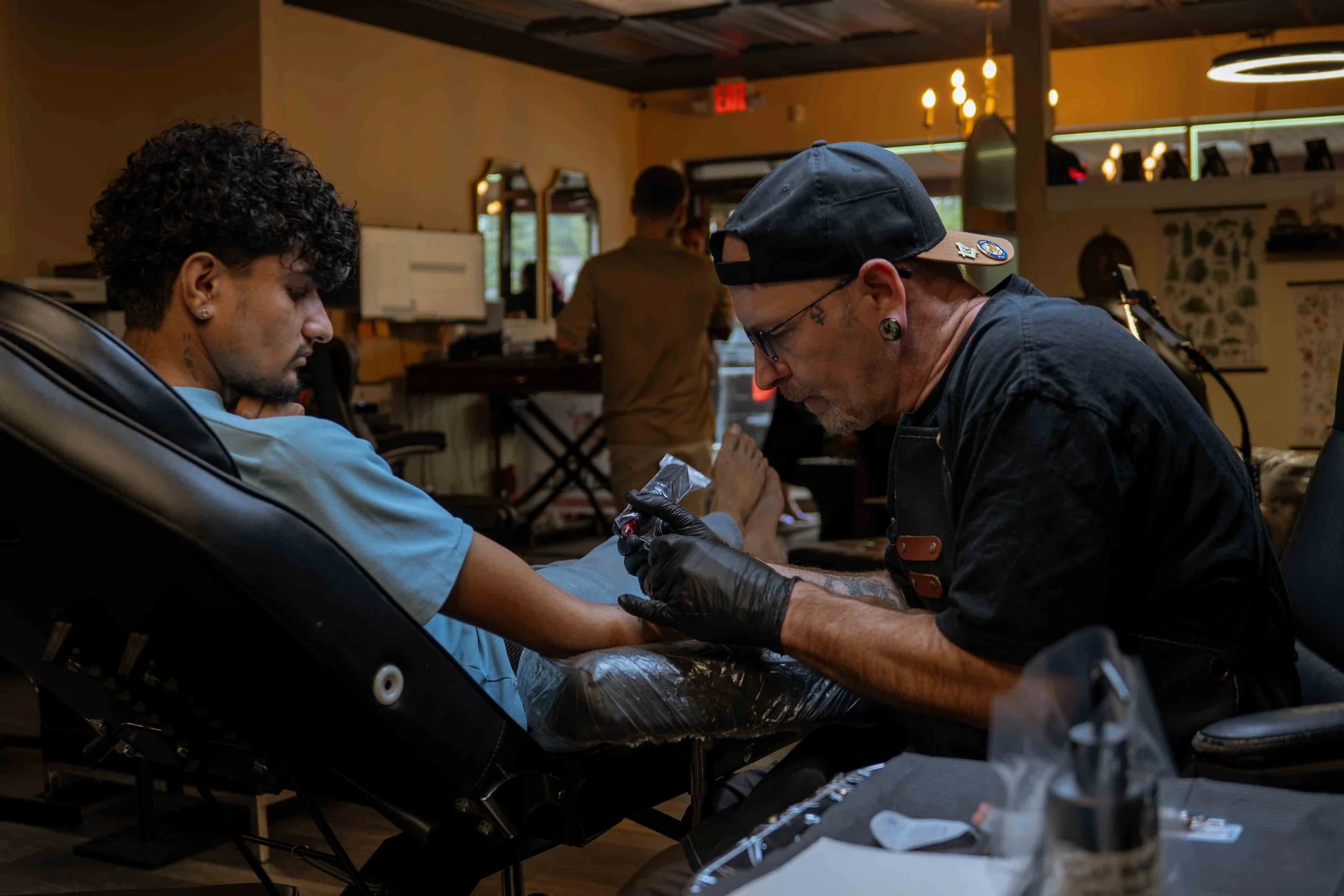 Tattoo artist working on a client's arm in a studio.
