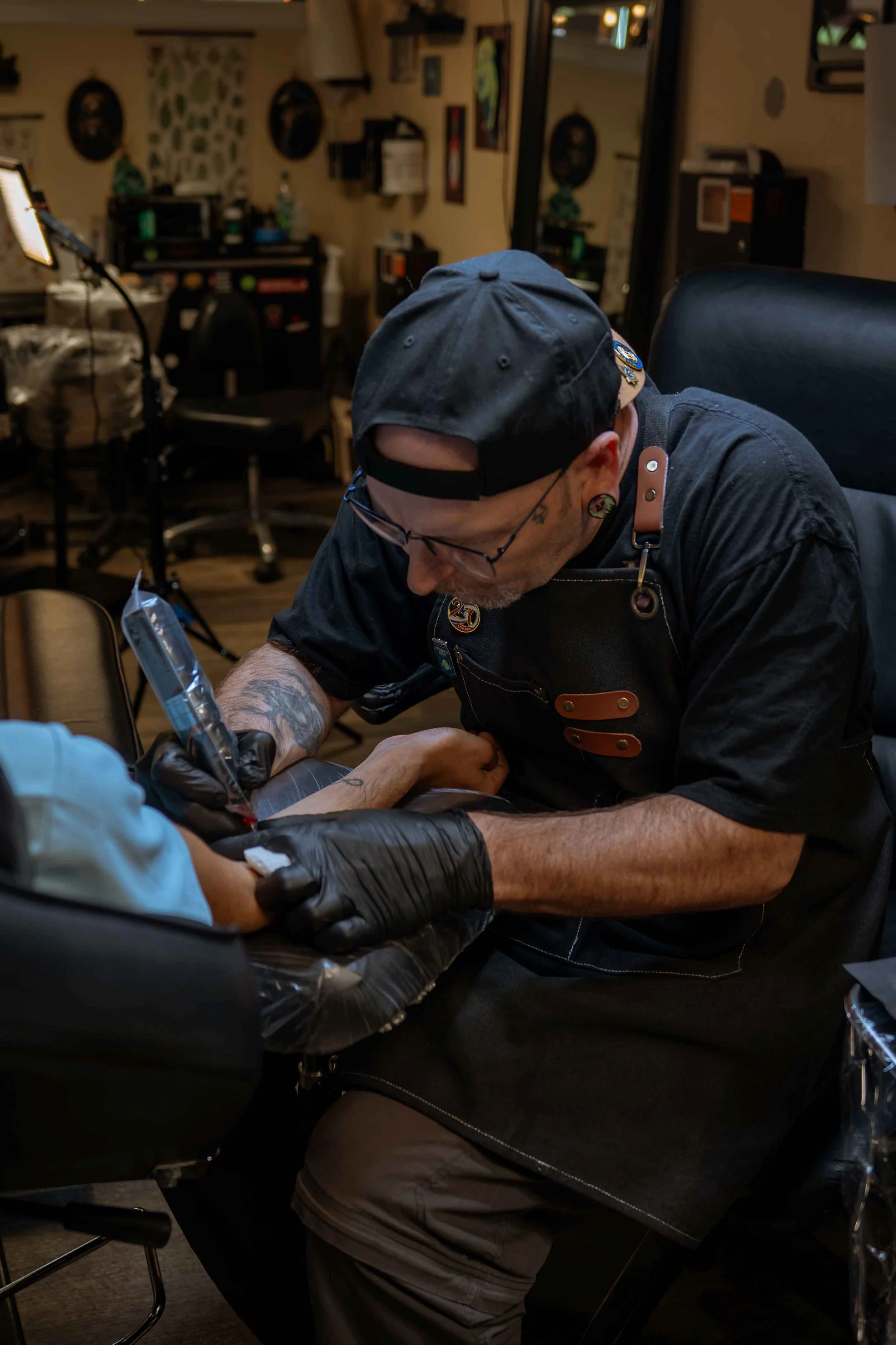 Tattoo artist working on a client at a studio workstation.