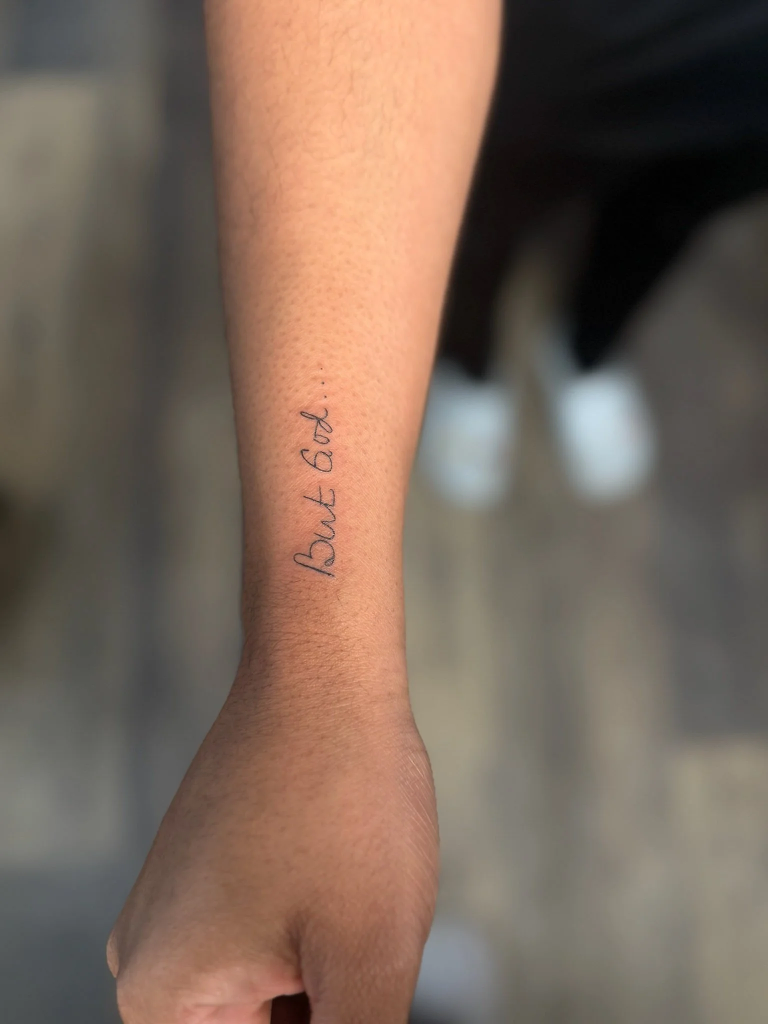 Close-up of a forearm with a tattoo that reads 'Born to' in cursive handwriting.