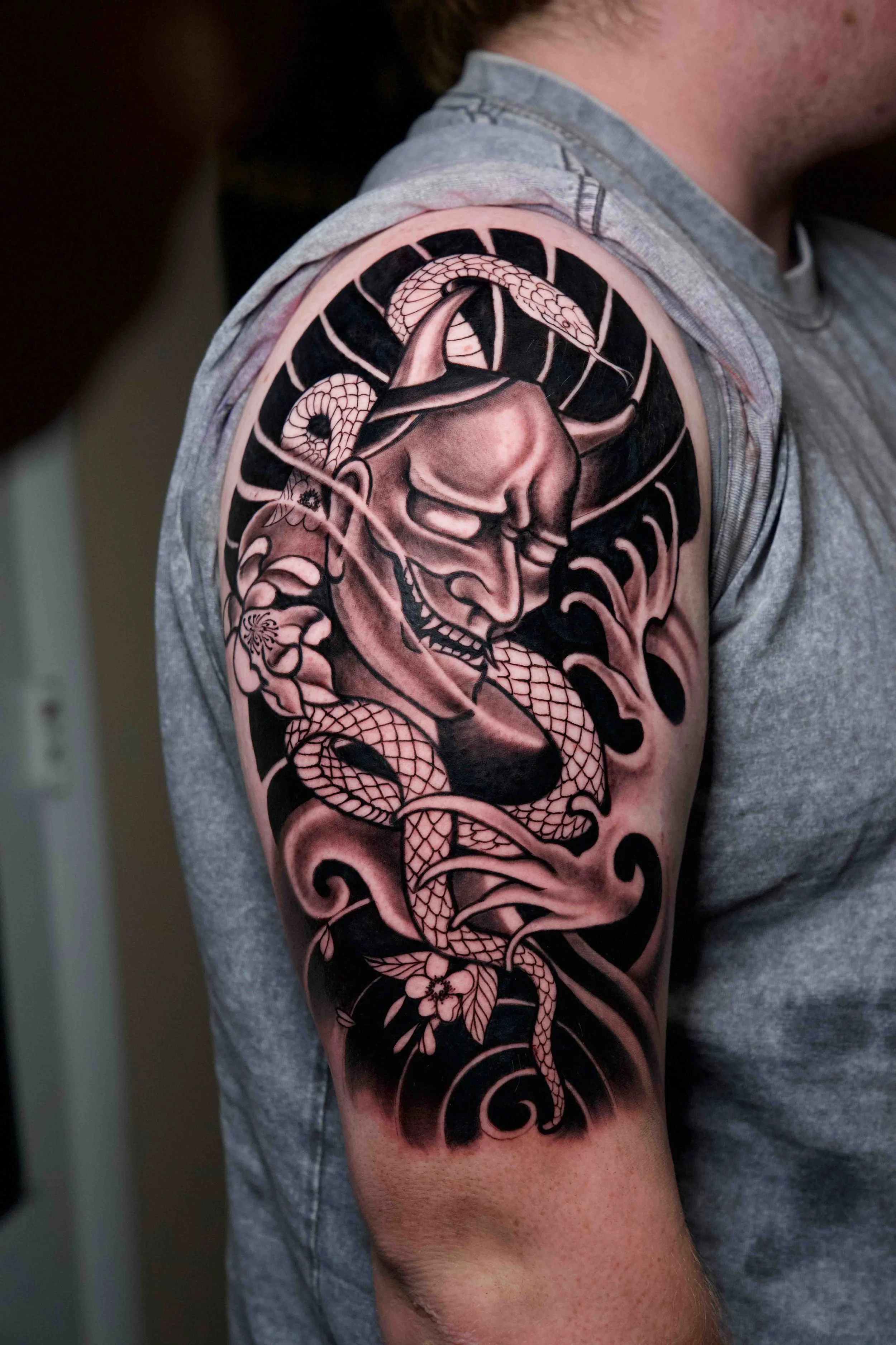 Detailed Japanese Hannya mask tattoo with shading on the upper arm.