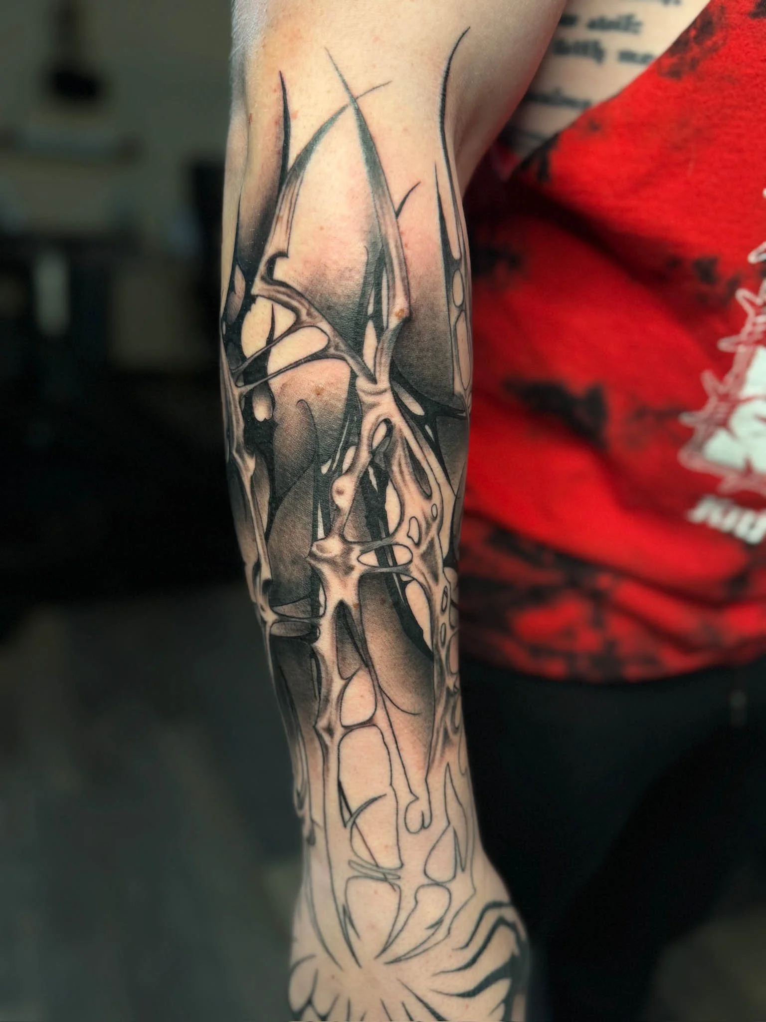 Tattoo of abstract skull and floral design on a person's arm.