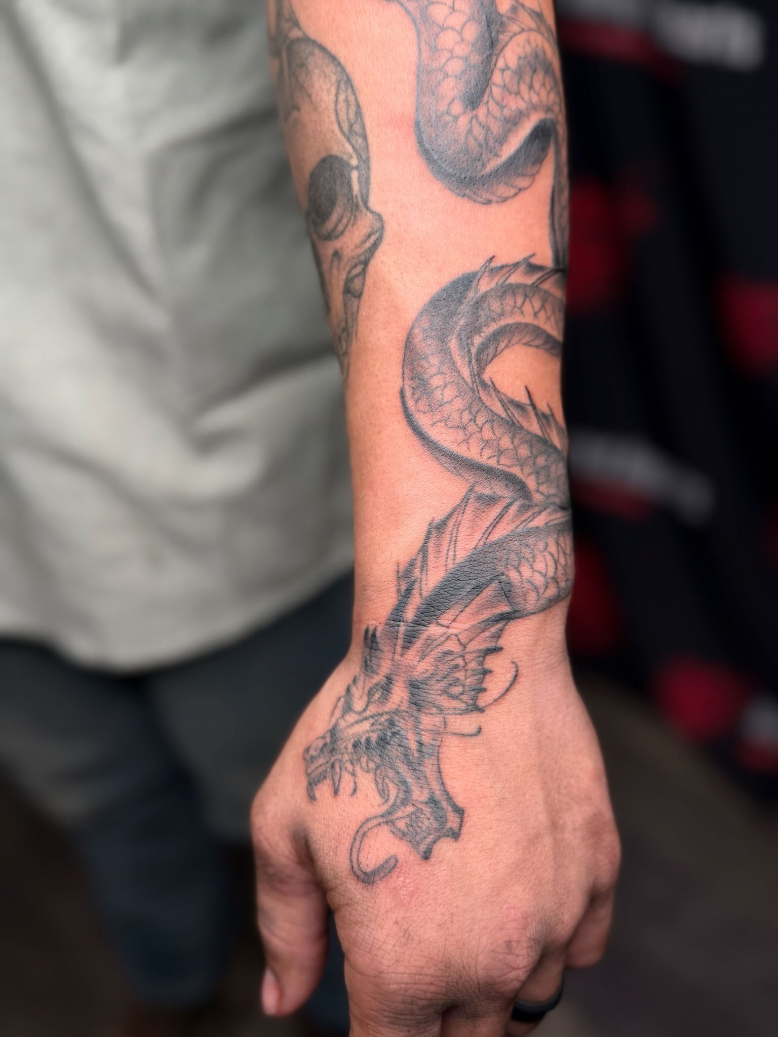 Tattoo of a dragon on the person's forearm.