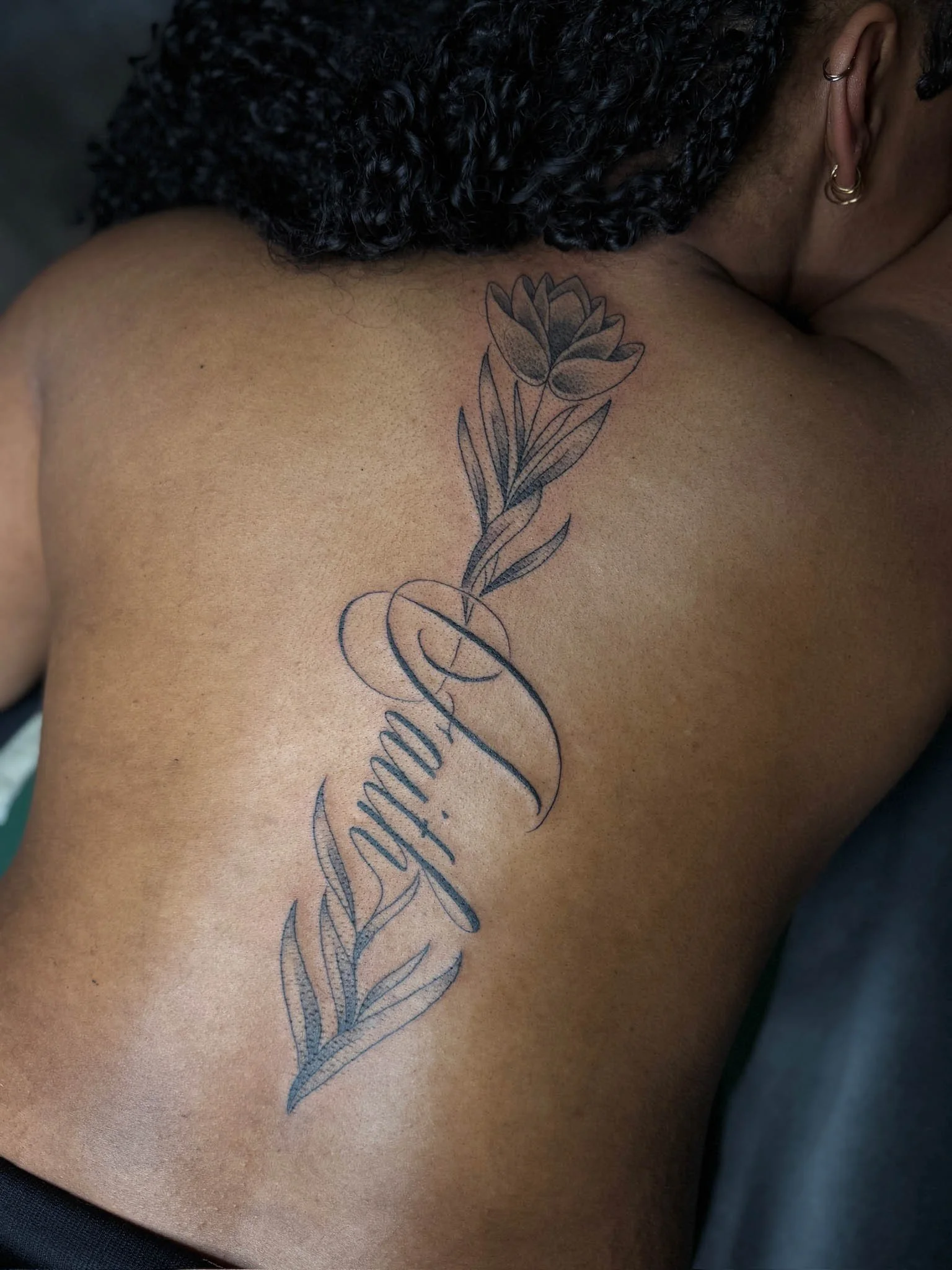 A tattoo of flowers and cursive text on a person's back.