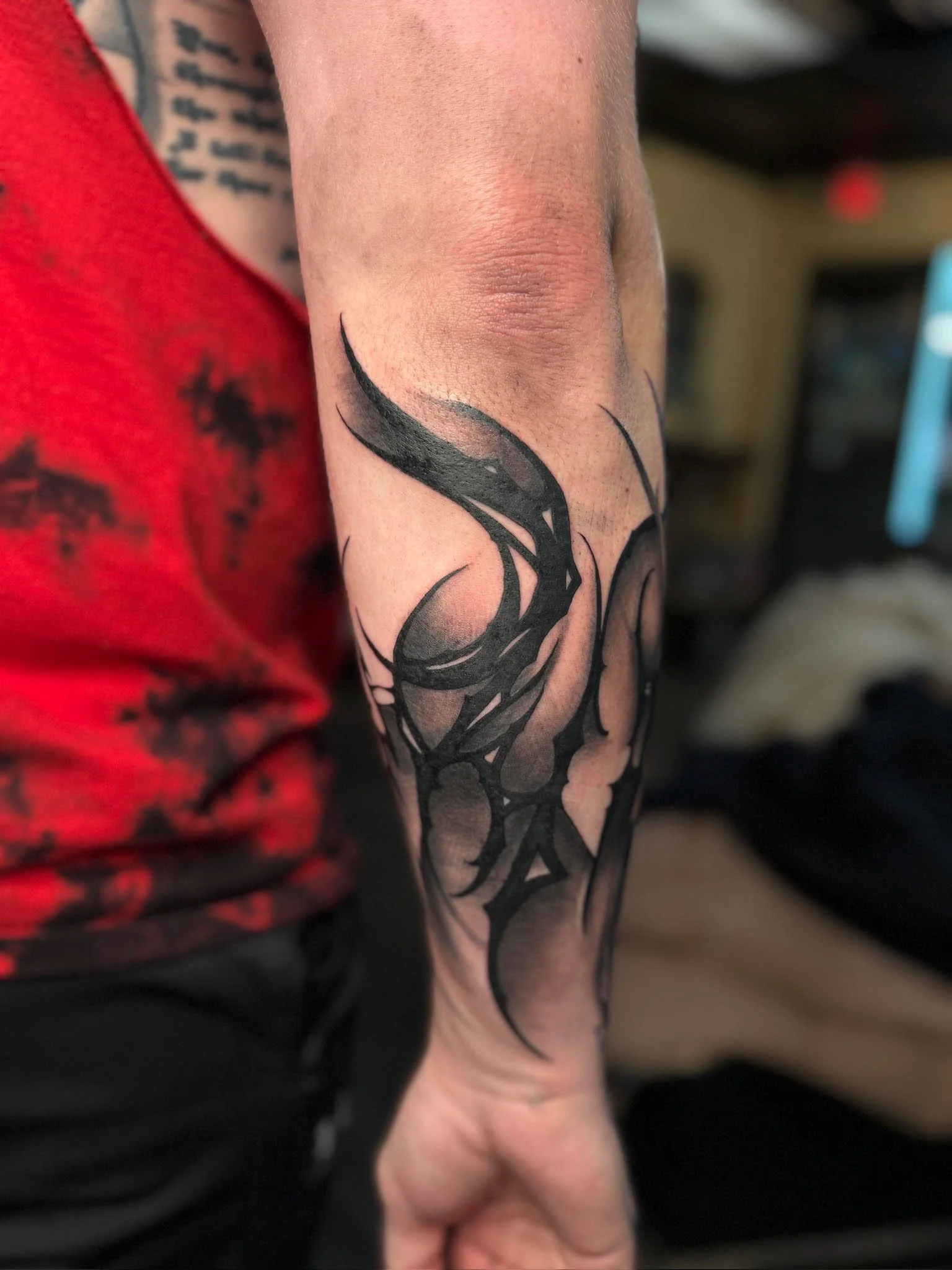 Black tribal-style tattoo on the person's forearm.