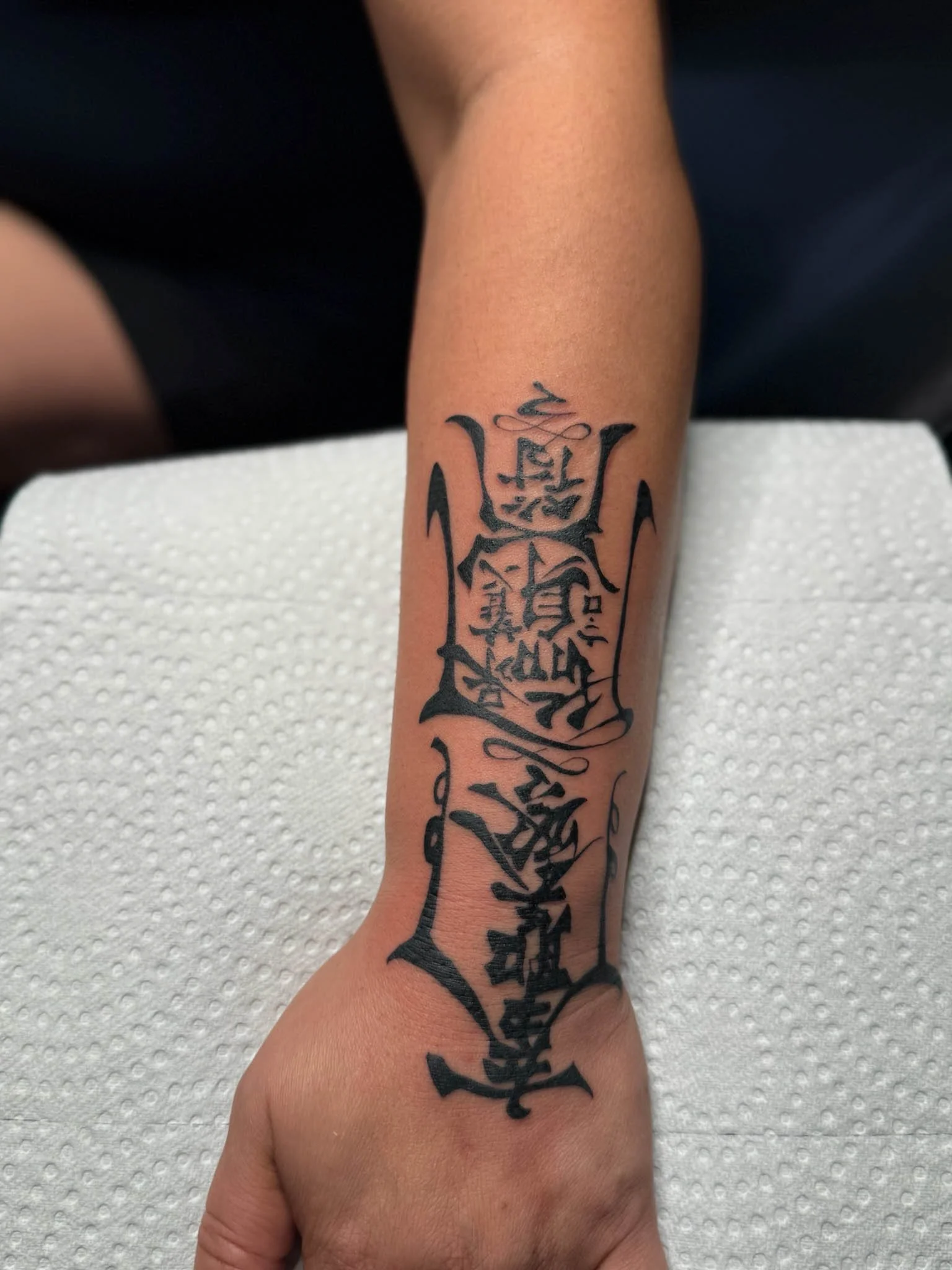 A tattoo on a person's forearm with black ink featuring Japanese characters arranged vertically.