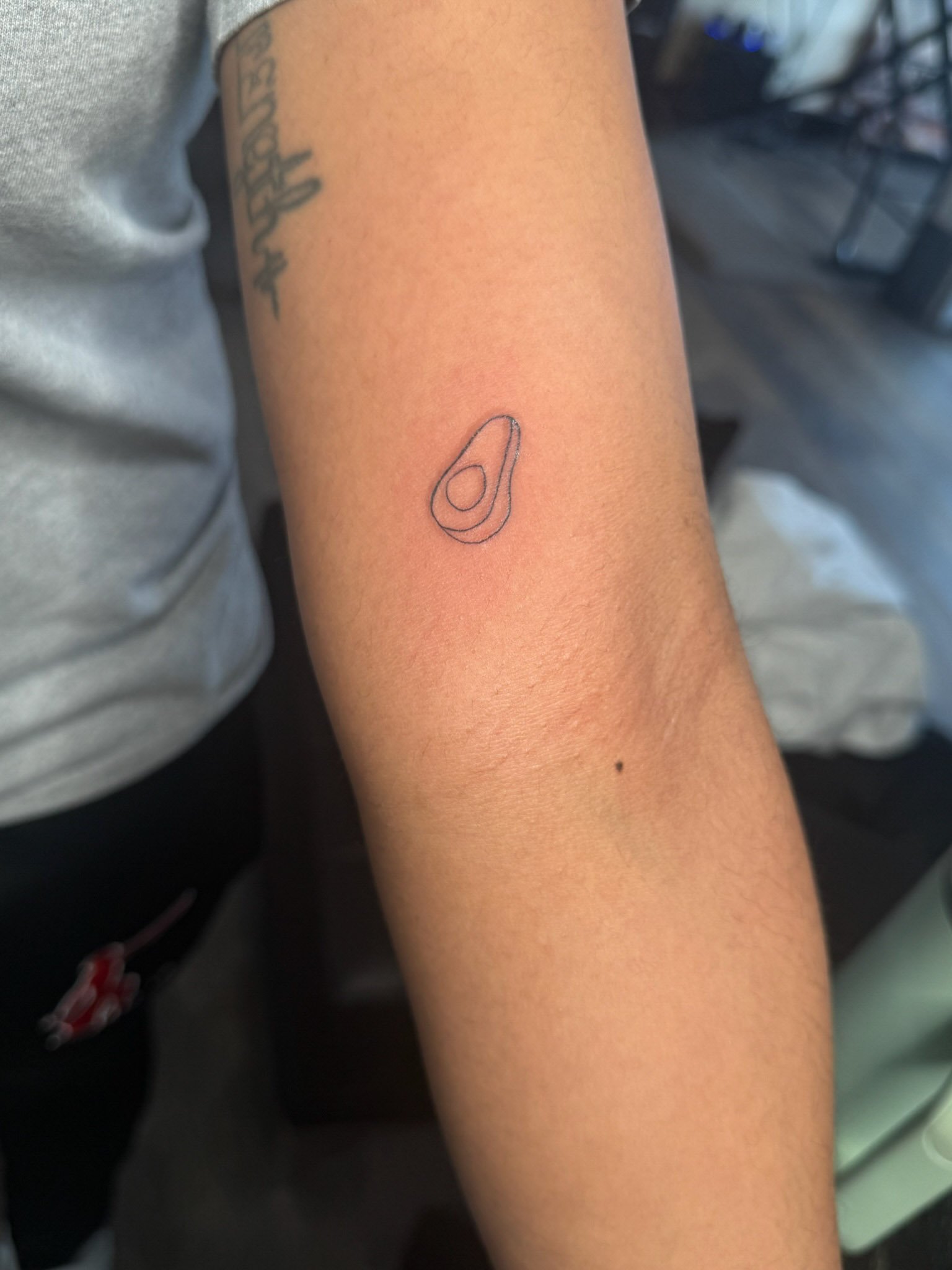 Small tattoo of an avocado on a person's forearm.