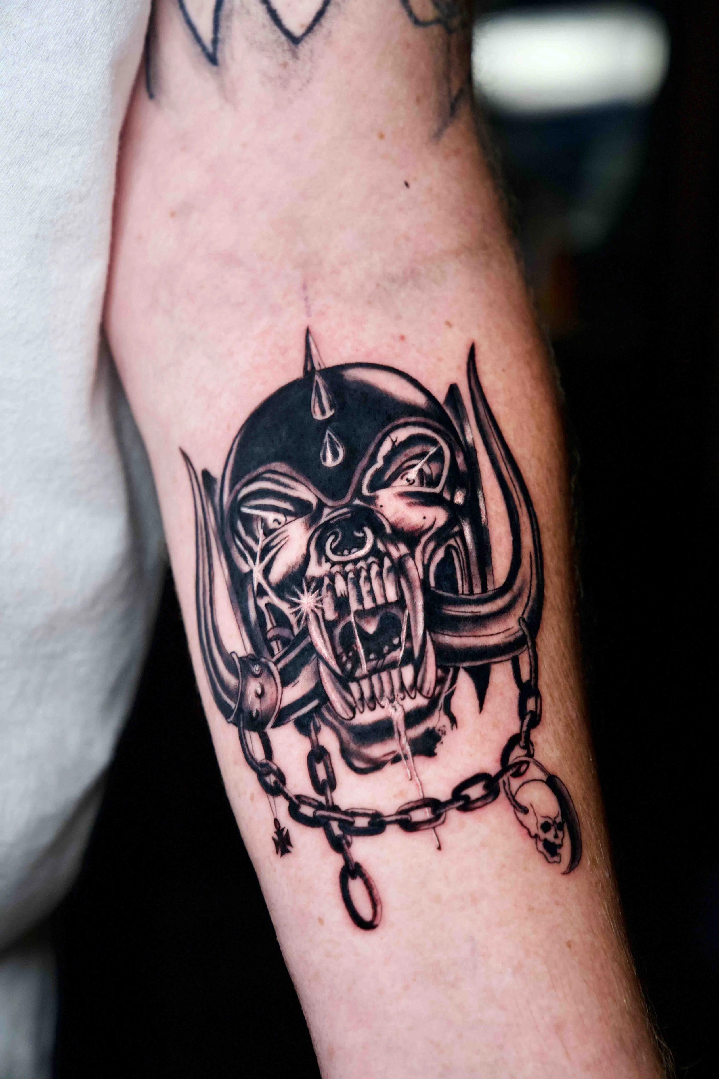 Close-up of a dark illustrative mask tattoo on an arm.