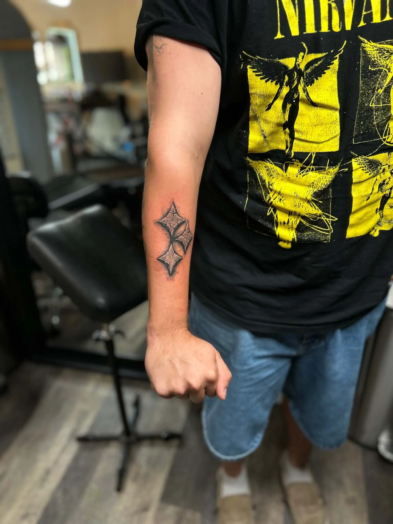 Forearm tattoo on a person wearing a yellow graphic t-shirt