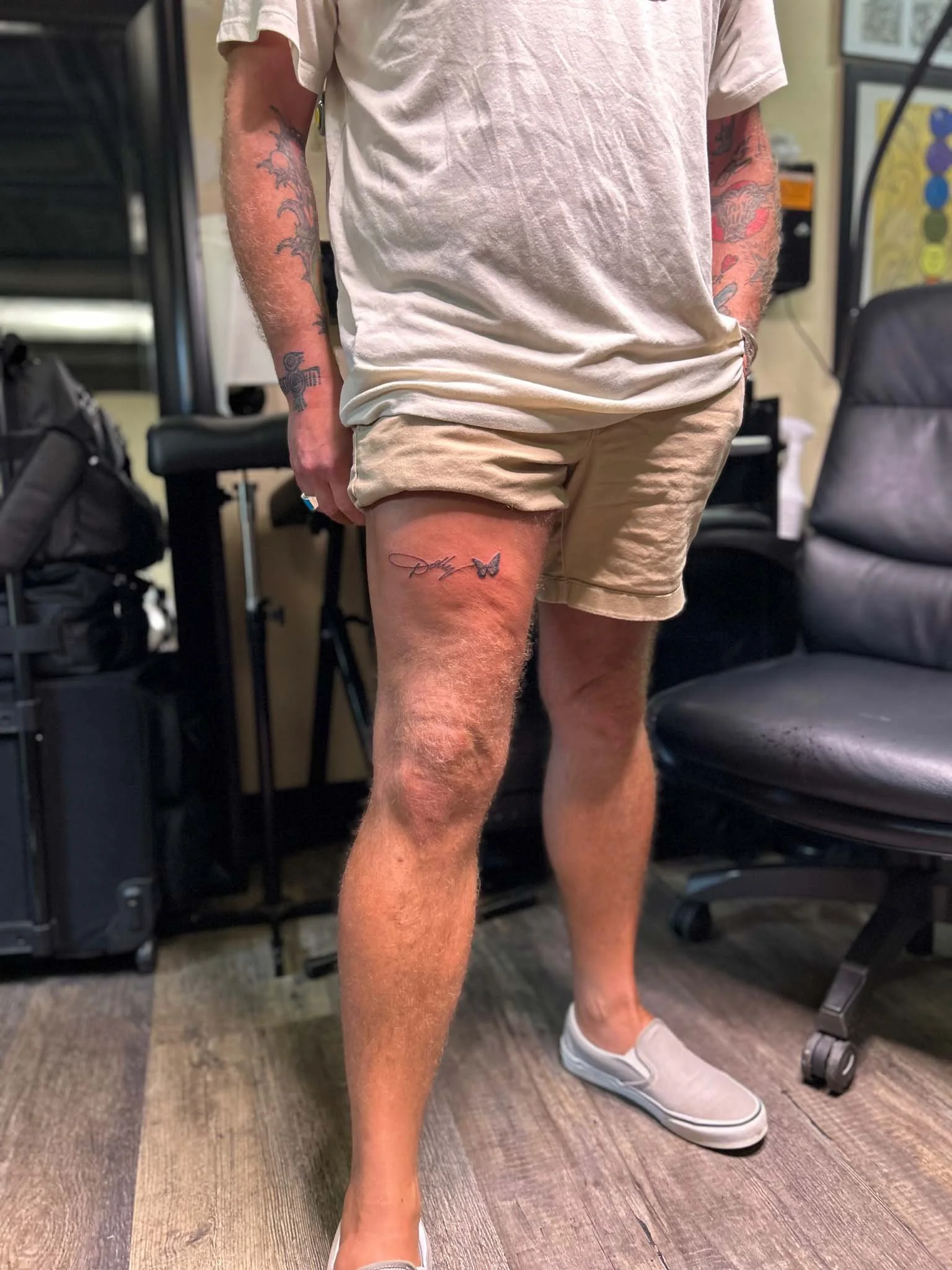 Person in shorts displaying a script leg tattoo with butterfly