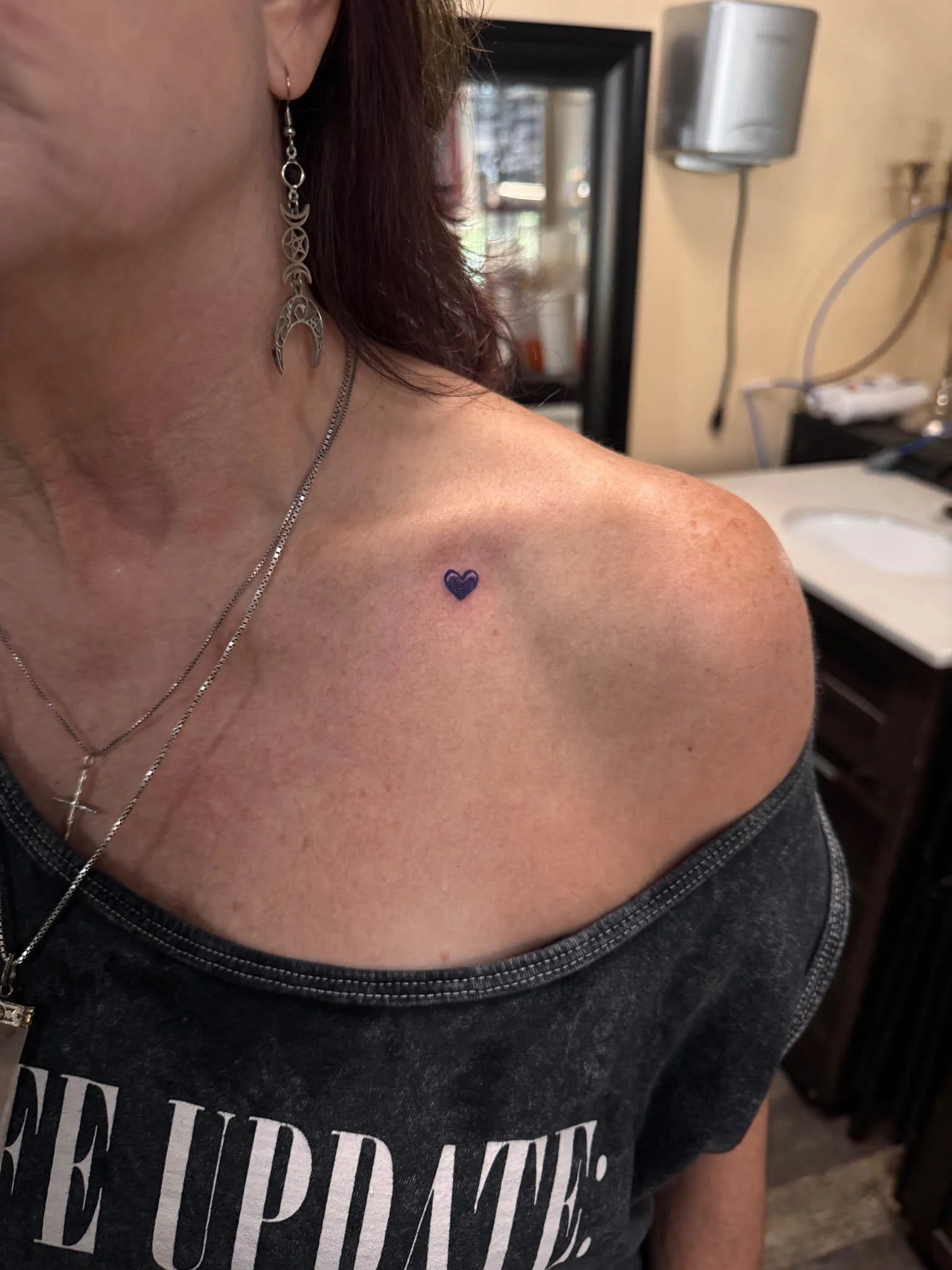 Minimalist heart tattoo on collarbone