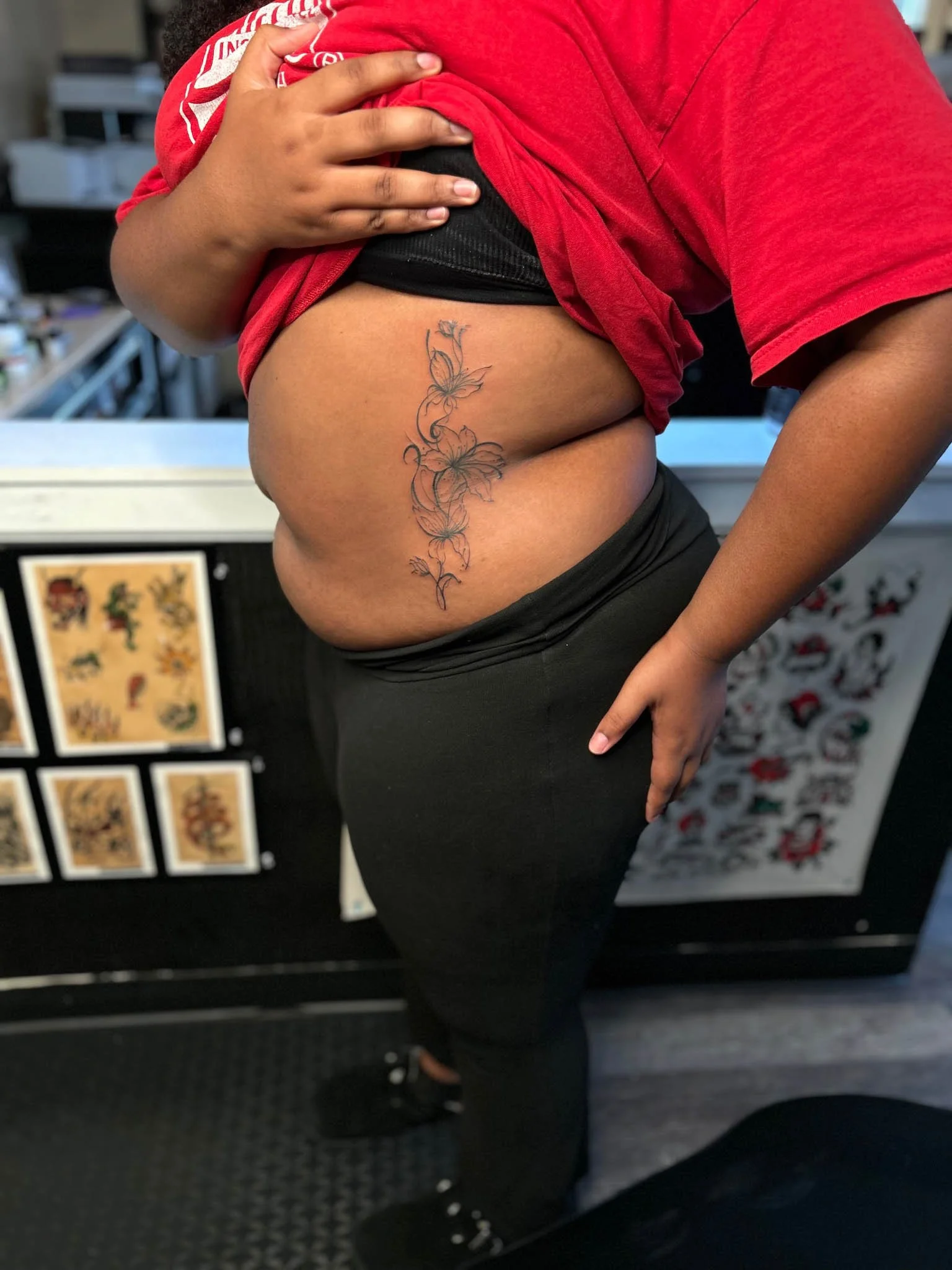Delicate fine-line floral tattoo running vertically along the side of a person's torso and ribcage.