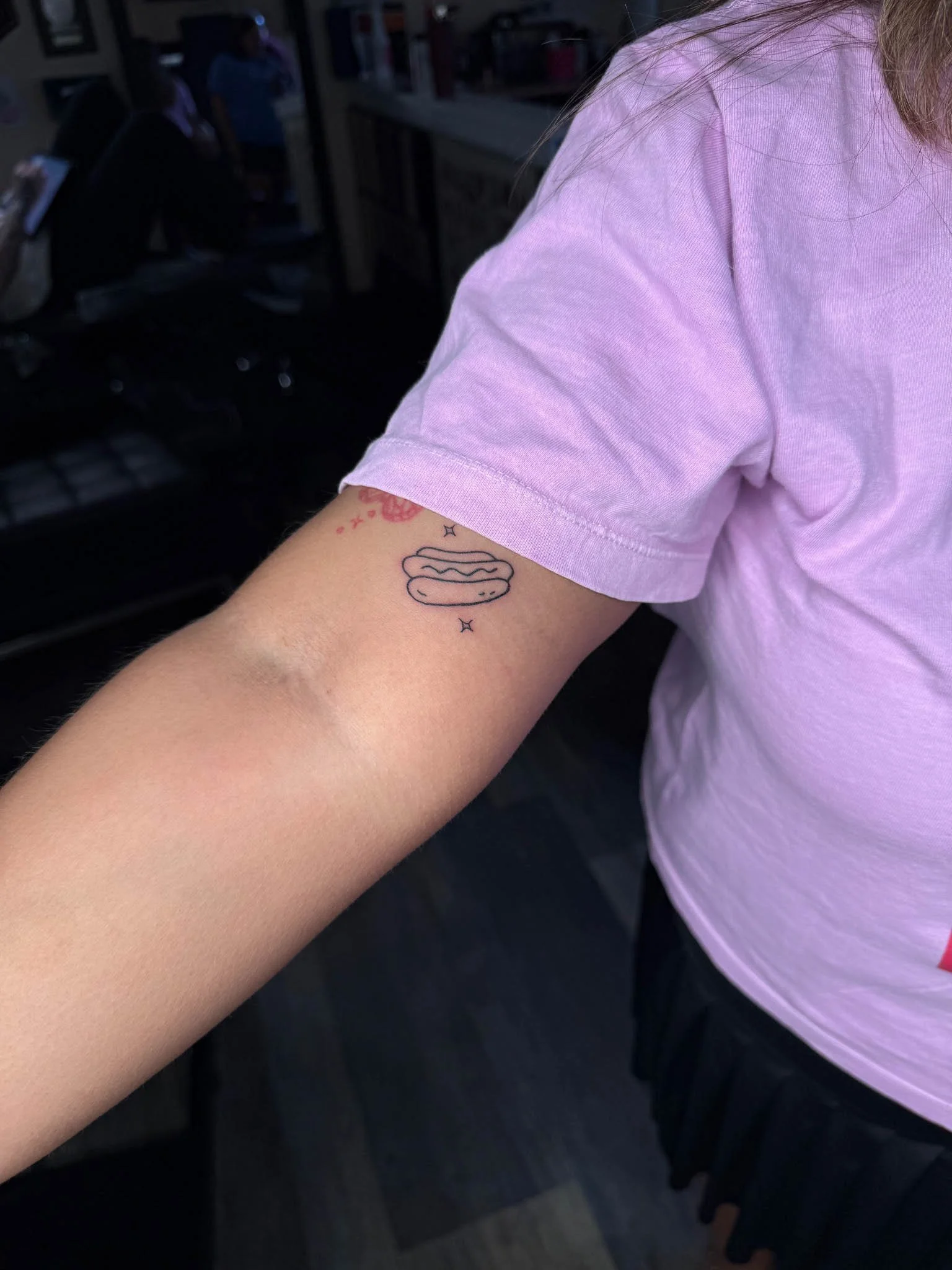 Inner arm fineline tattoo on a person wearing a purple shirt