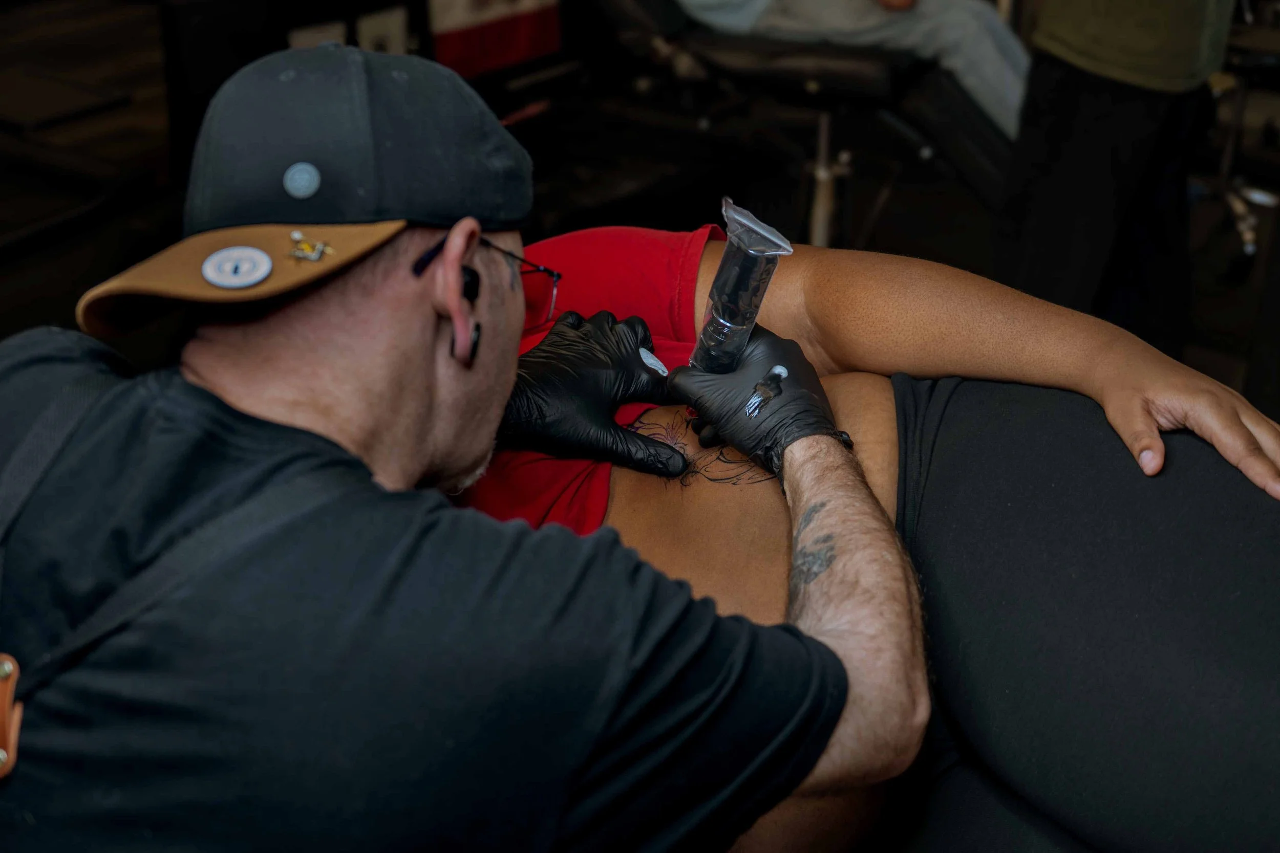 Tattoo artist working on a client's torso in a studio