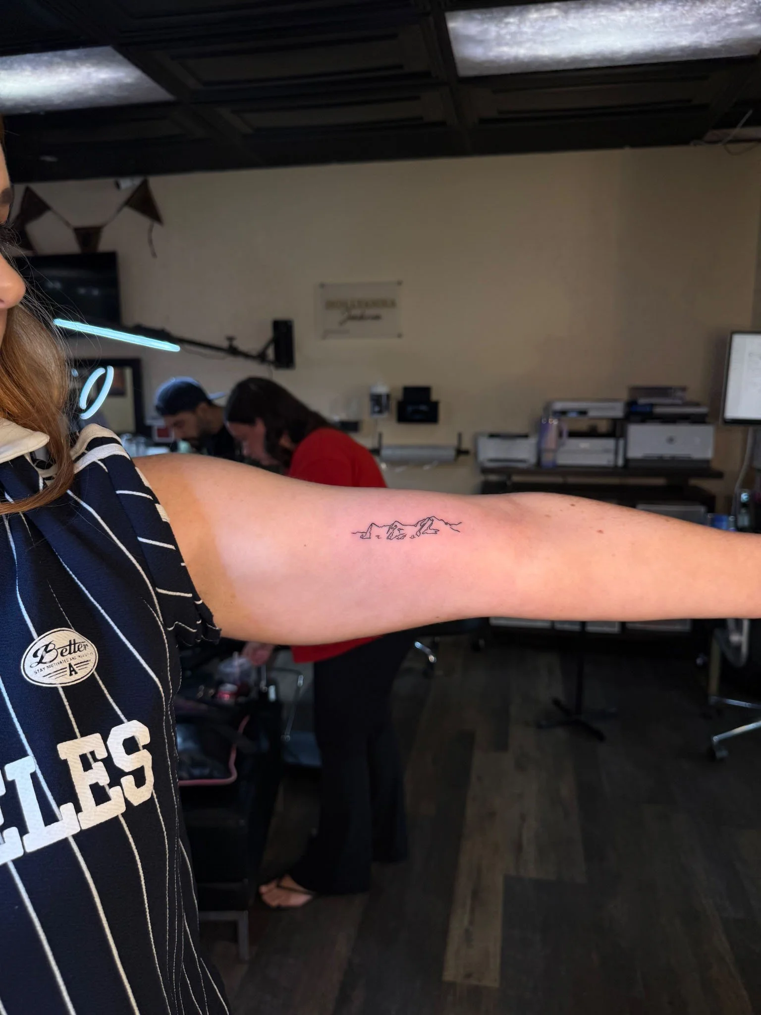 Minimalist mountain tattoo on upper arm
