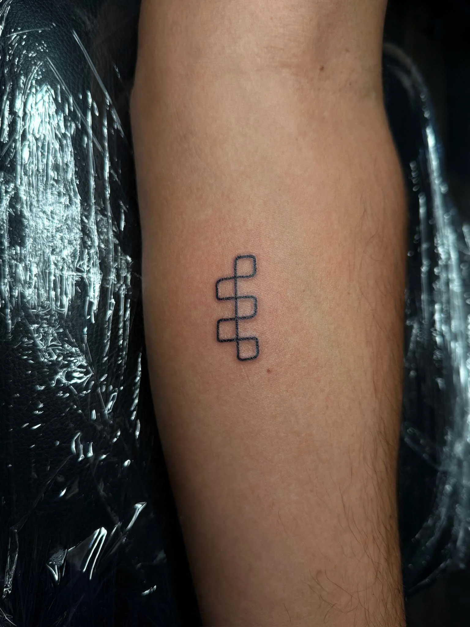 Tattoo of a minimalist geometric design on a person’s forearm.