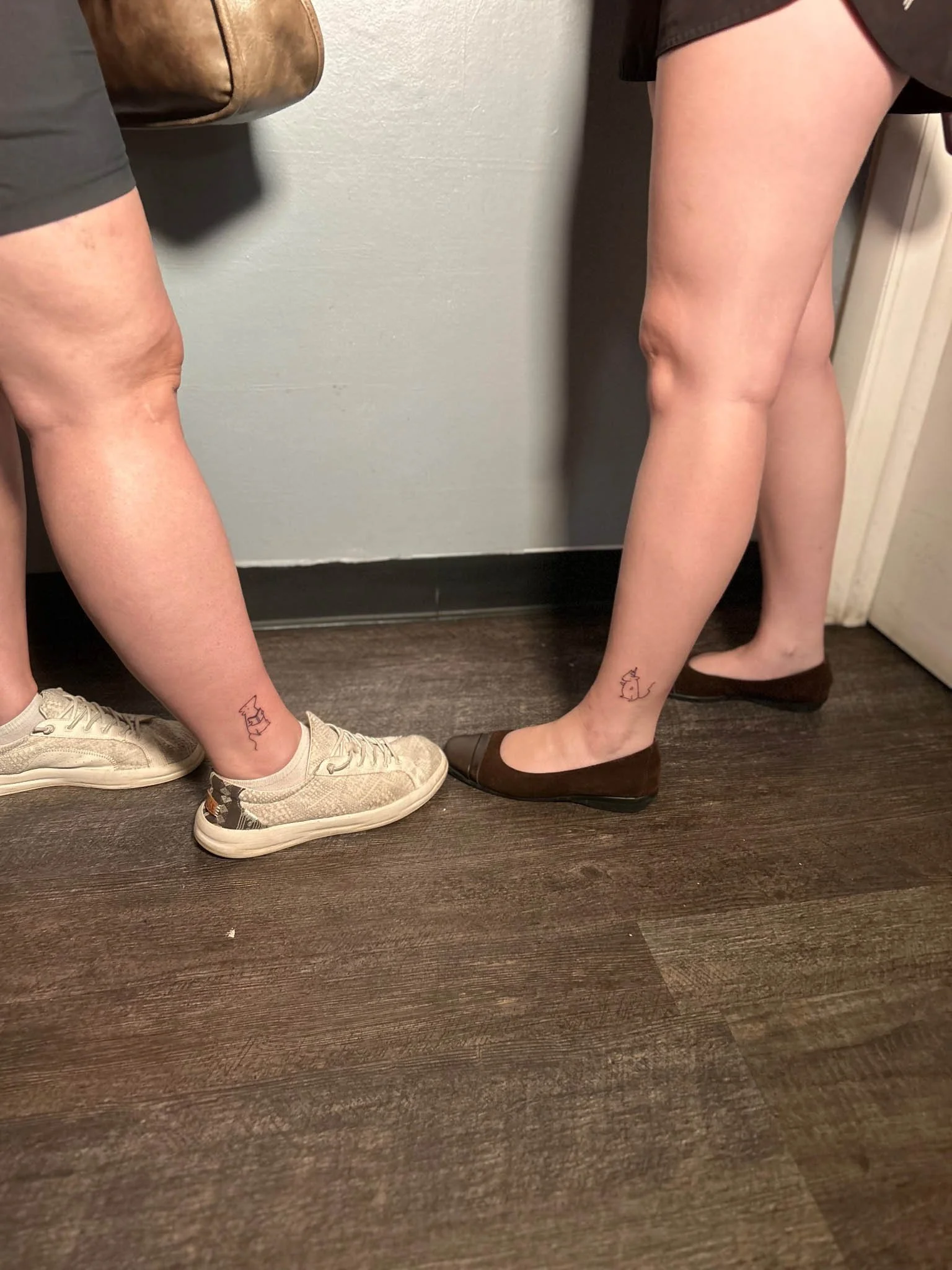 Lower legs showing subtle line tattoos above the ankles.