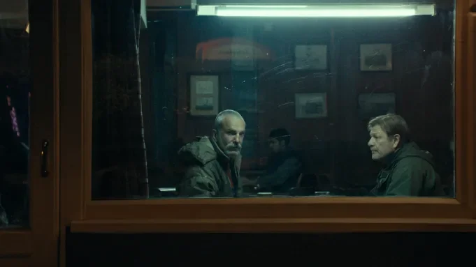 Two men sitting in a diner looking out the window