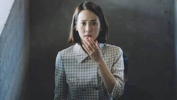 A still from the film Parasite of a woman with her hand near her mouth expressing shock