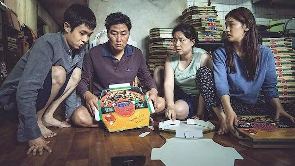 A family folding pizza boxes in the movie Parasite