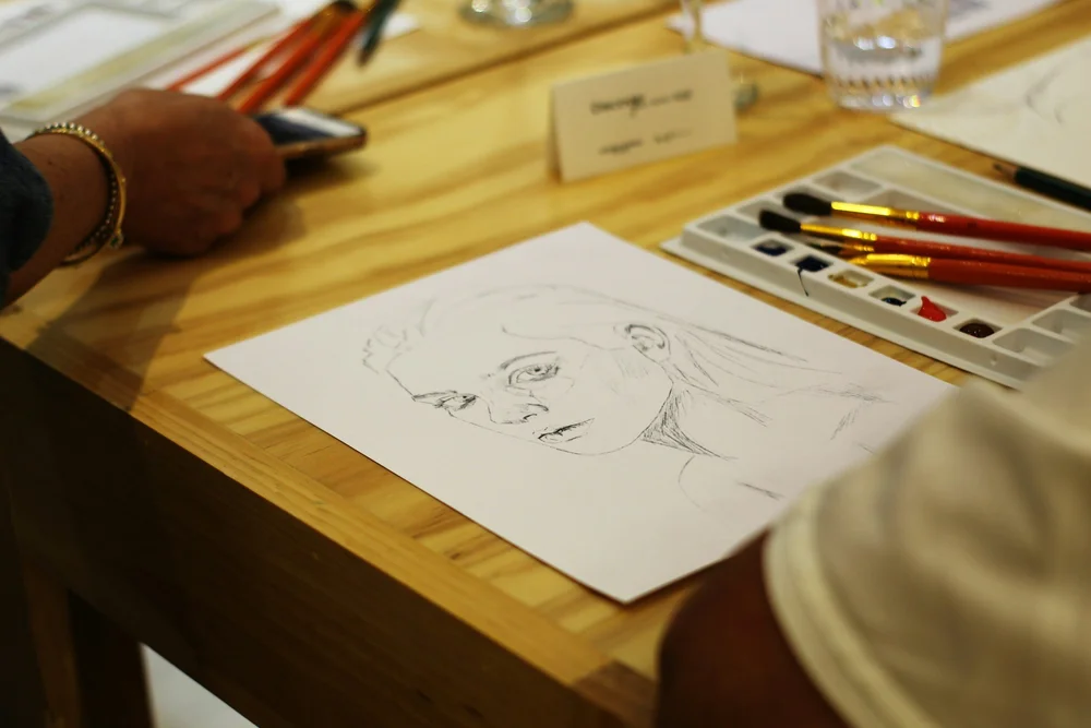 A portrait sketch and art supplies on a table