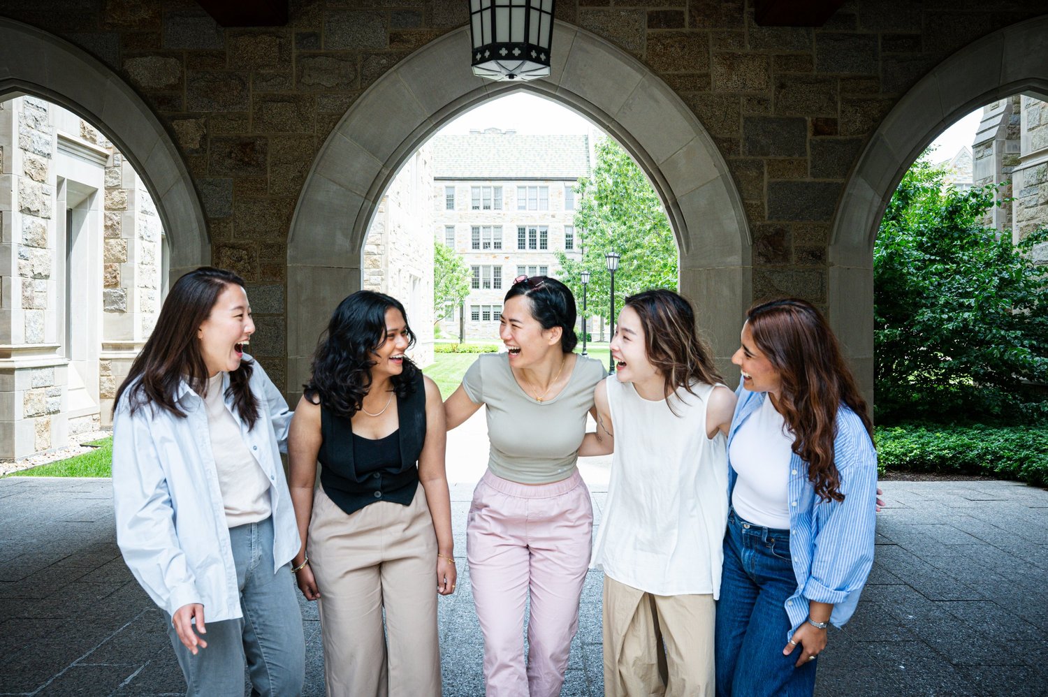 Five Dear Therapy team members sharing a laugh beneath a stone archway.