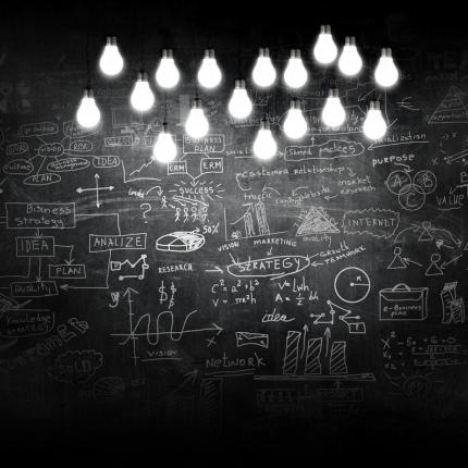 Bright hanging lightbulbs shine over a chalkboard filled with brainstorming sketches and business strategies.