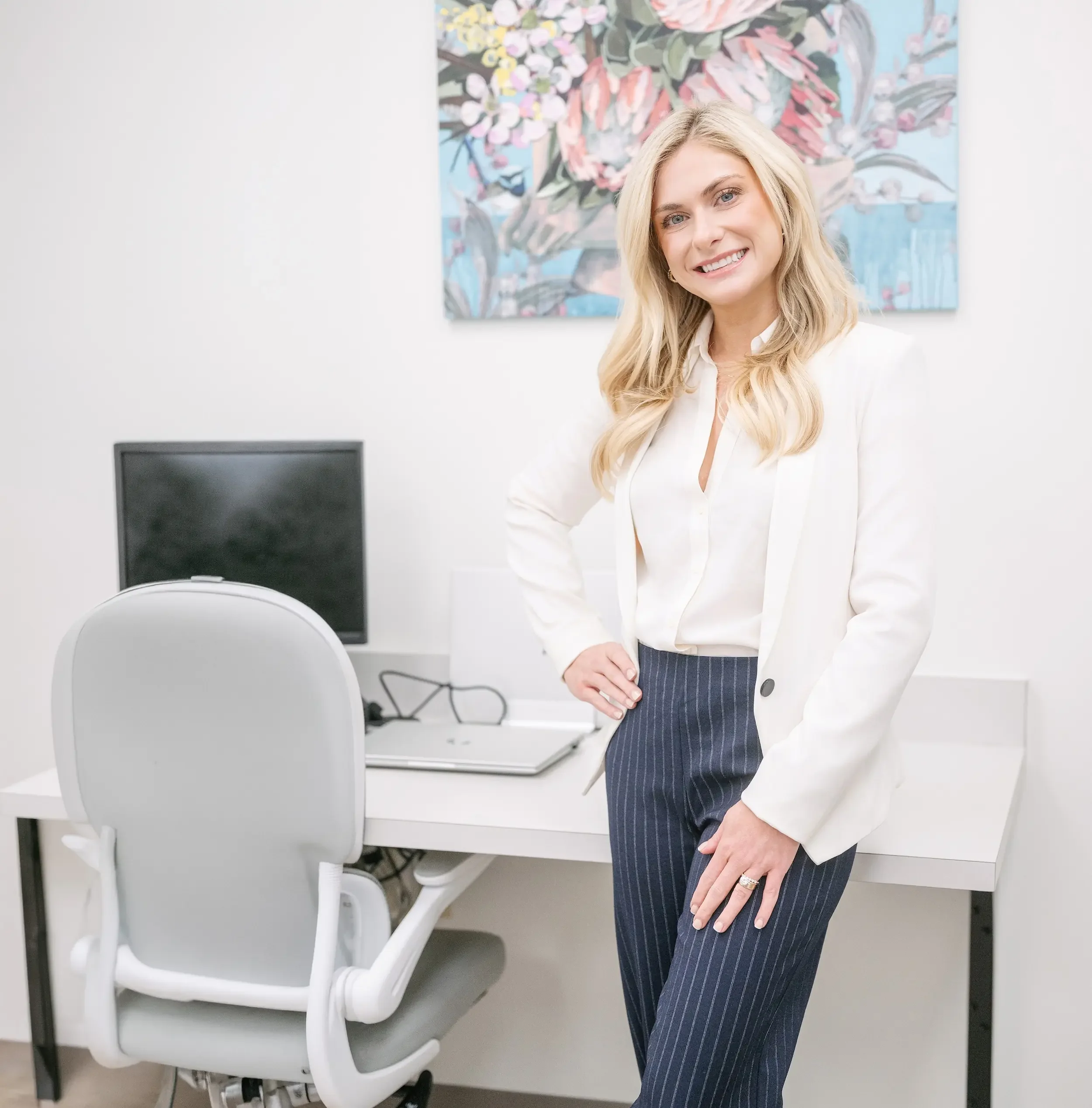 Maggie Theriot, DNP, FNP-C, women's health nurse practitioner in Metairie, LA, standing in a Signature Health office in a white blazer
