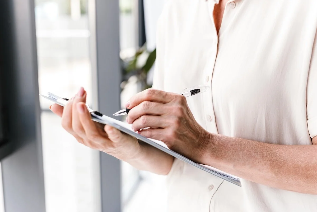 A woman filling out her Ms.Medicine health map on a clipboard.