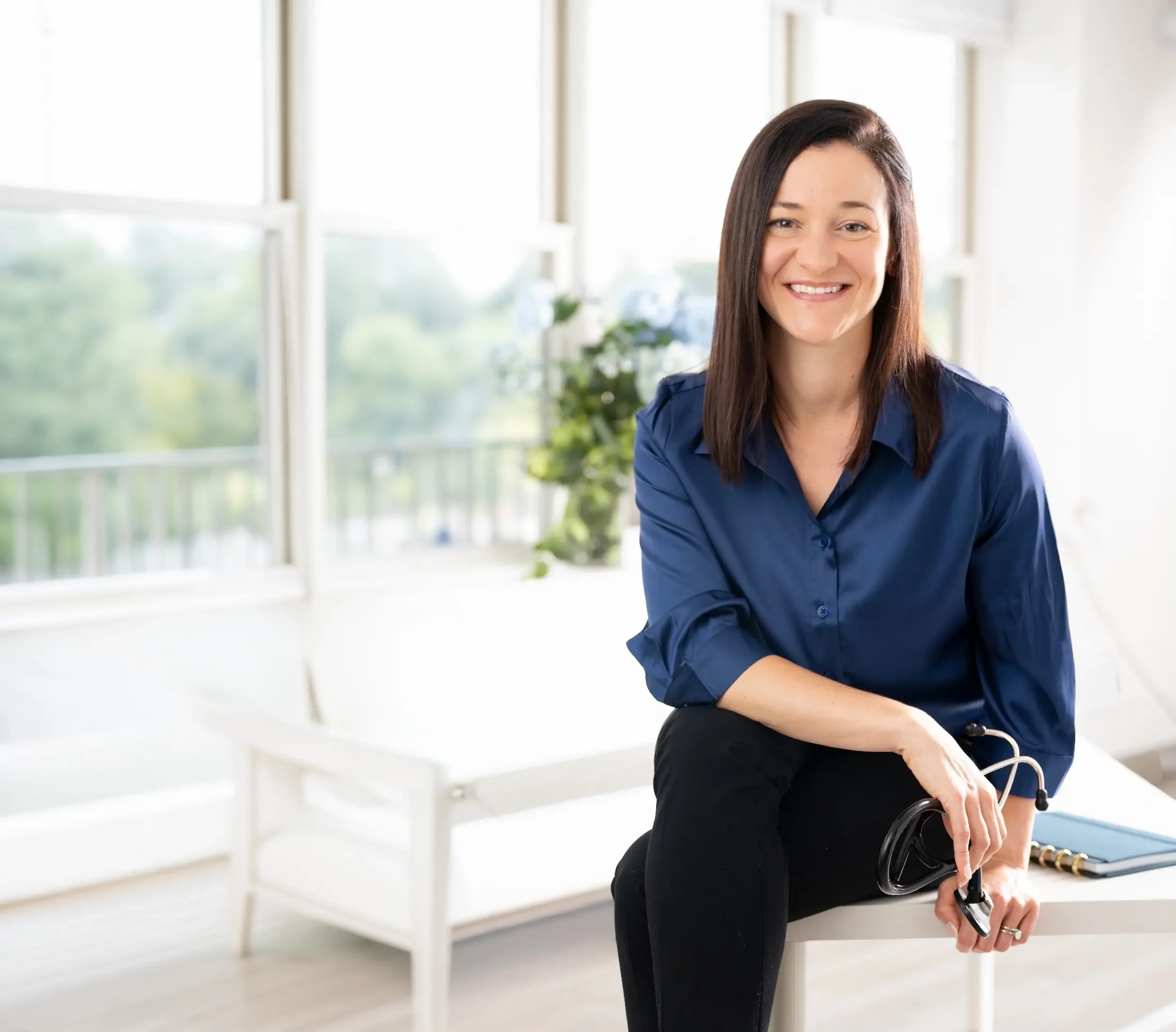 Dr. Kalyn Jolivette holding a stethoscope in a bright office at Concierge Medicine of Cincinnati