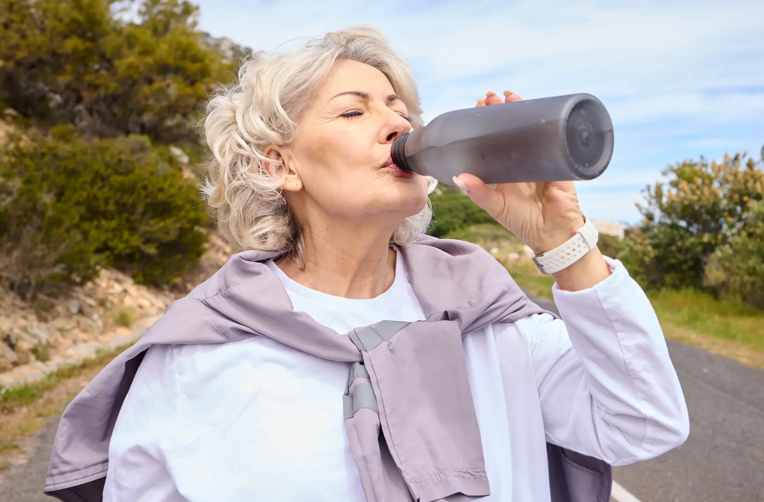 An older woman drinking out of a water bottle.
