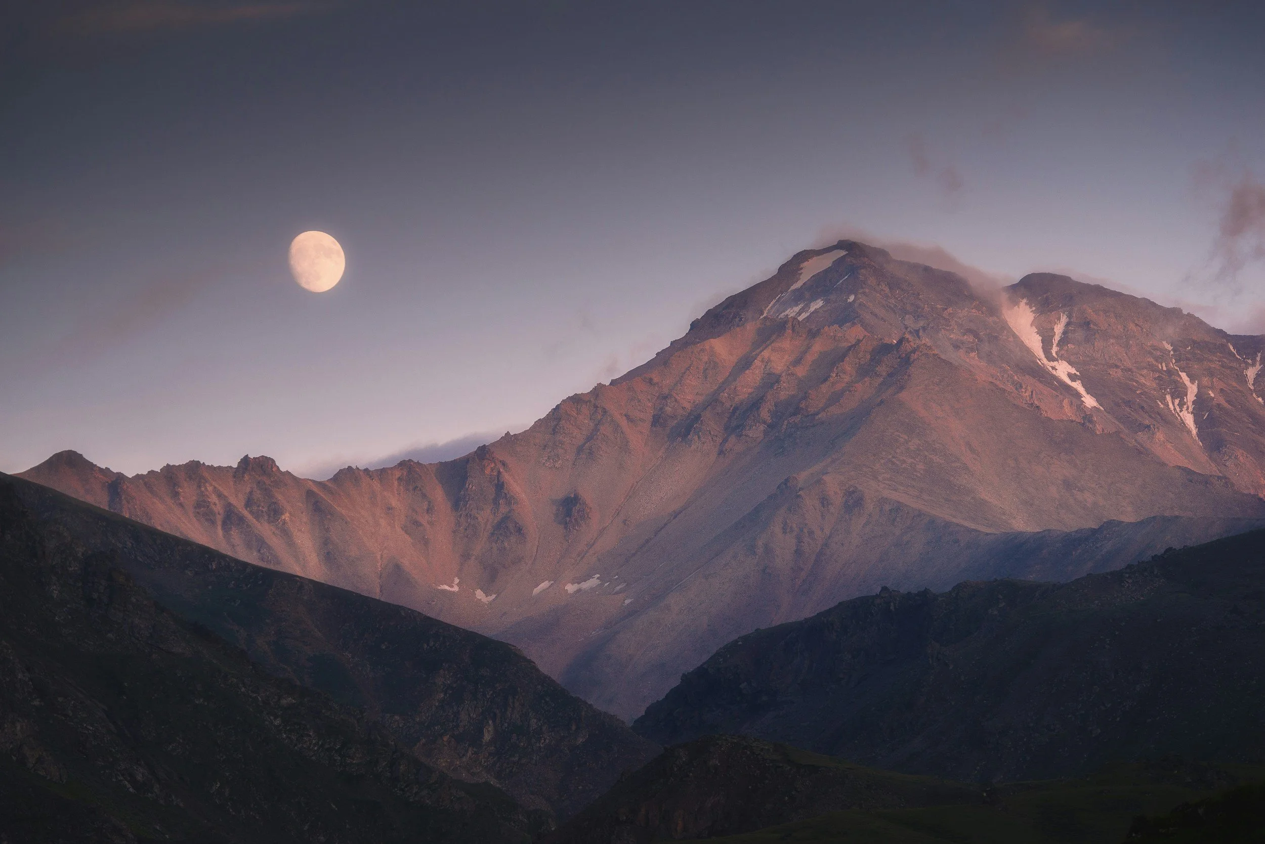 Montañas al anochecer con la luna llena en el cielo