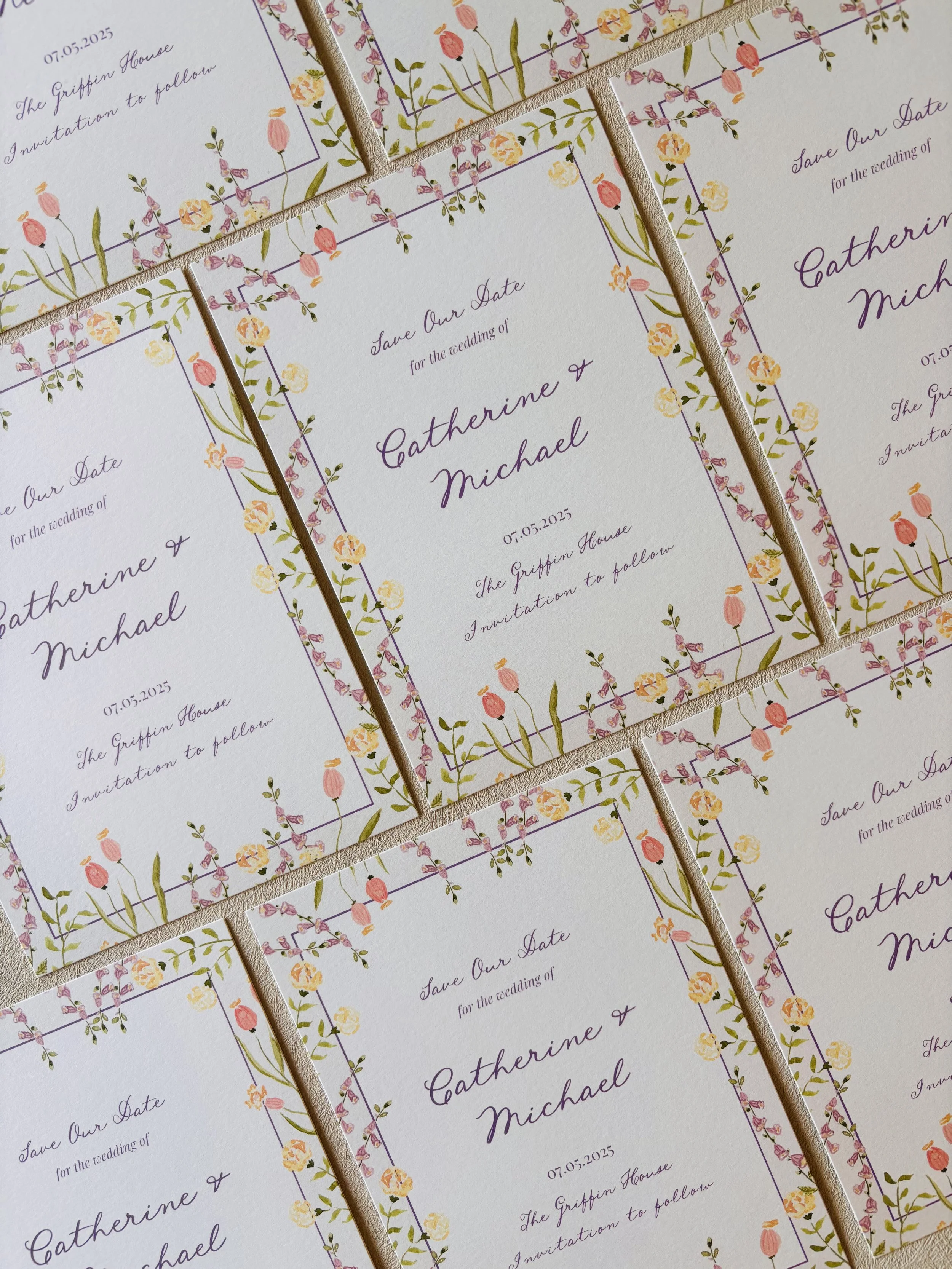 Multiple wedding save-the-date cards with floral borders and purple cursive text on a white background.