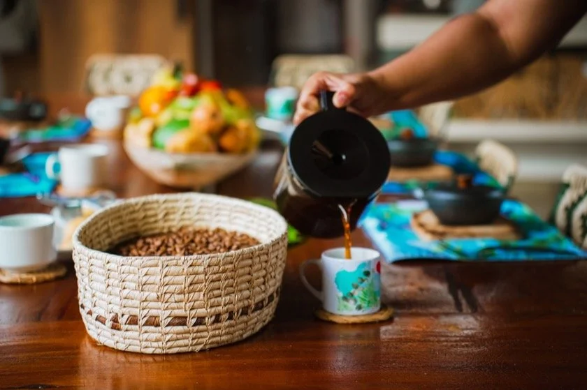 Café servido en la mesa de Araucana Lodge, junto a una canasta de granos de café y frutas frescas.