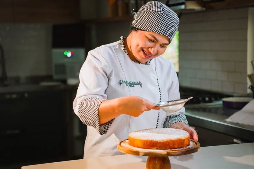 Una integrante del equipo de cocina de Araucana Lodge espolvorea azúcar sobre una torta recién horneada.