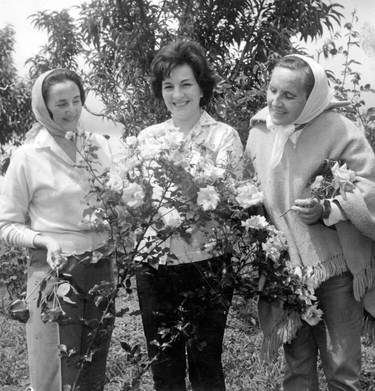 Alicia y otras dos mujeres entre rosales, en una fotografía en blanco y negro.