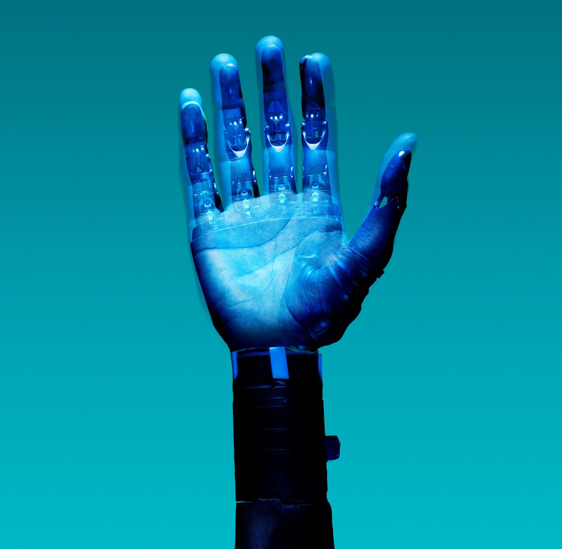 En högt teknologisk robotarm som håller upp en hand mot en blå bakgrund.