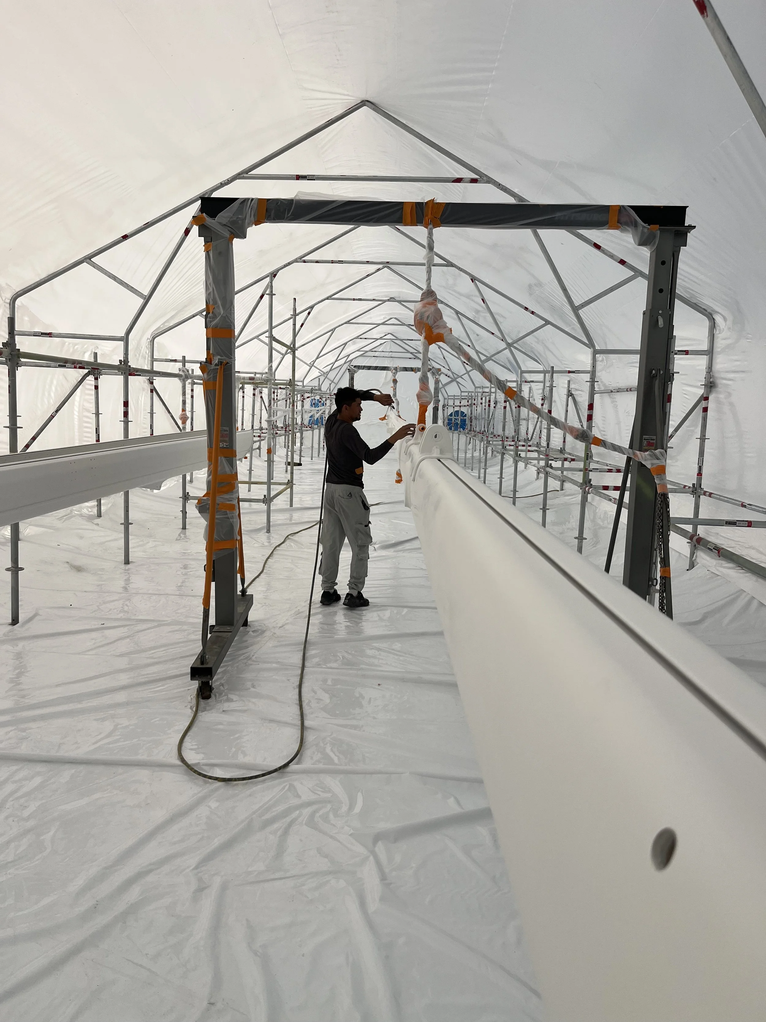 men applying finish coat to sailboat hull