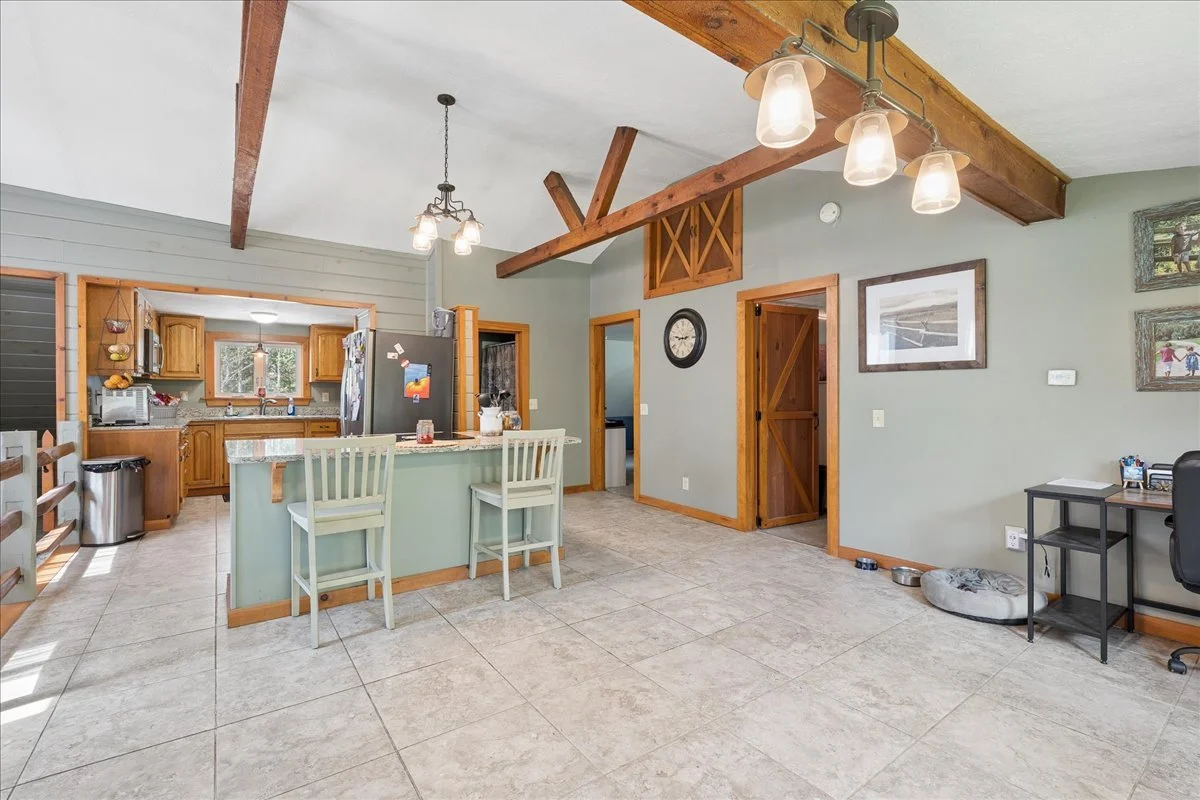 Open concept kitchen and dining area with wood accents, tiled flooring, and a light green painted wall.