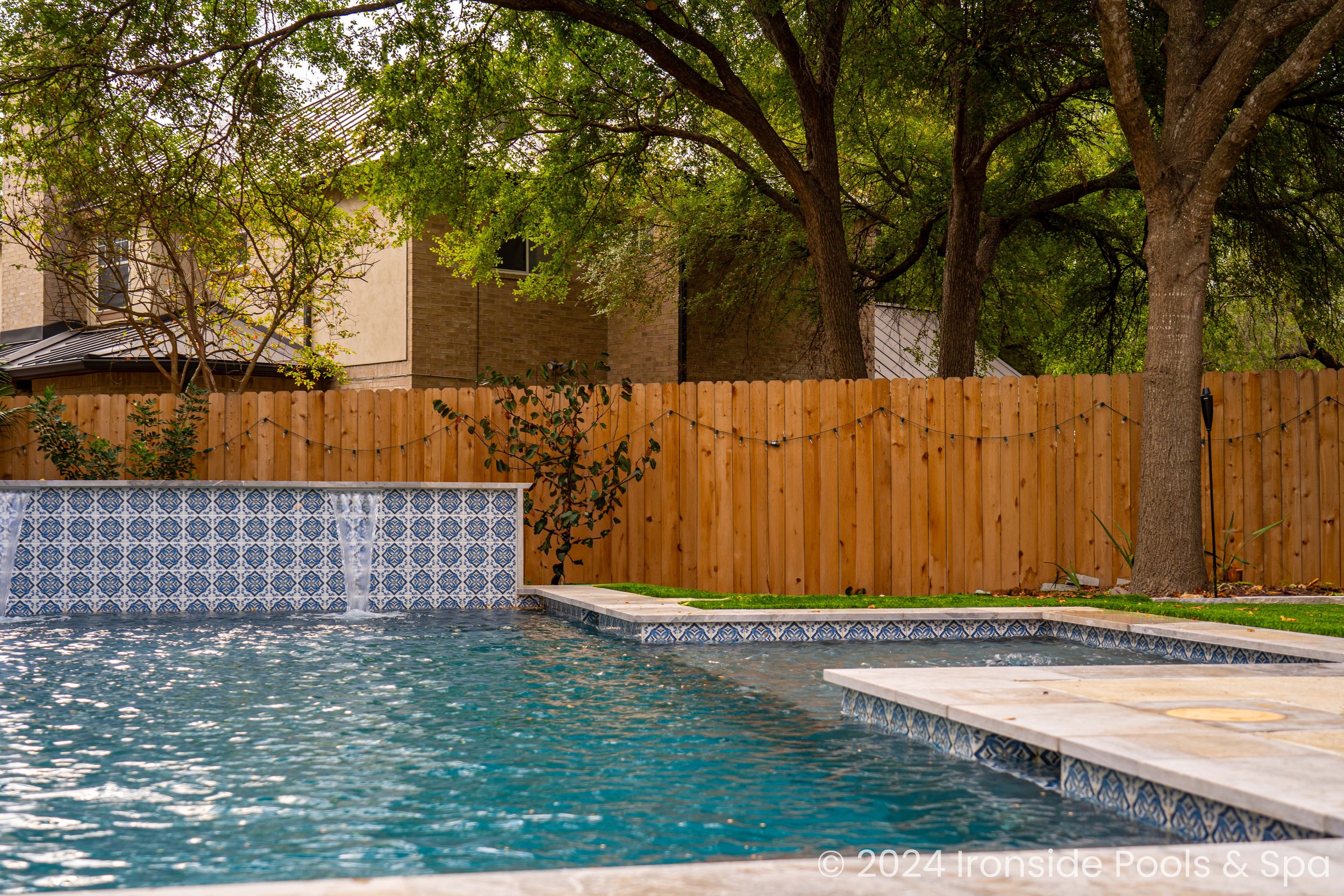 Backyard with pool, wooden fence, and trees